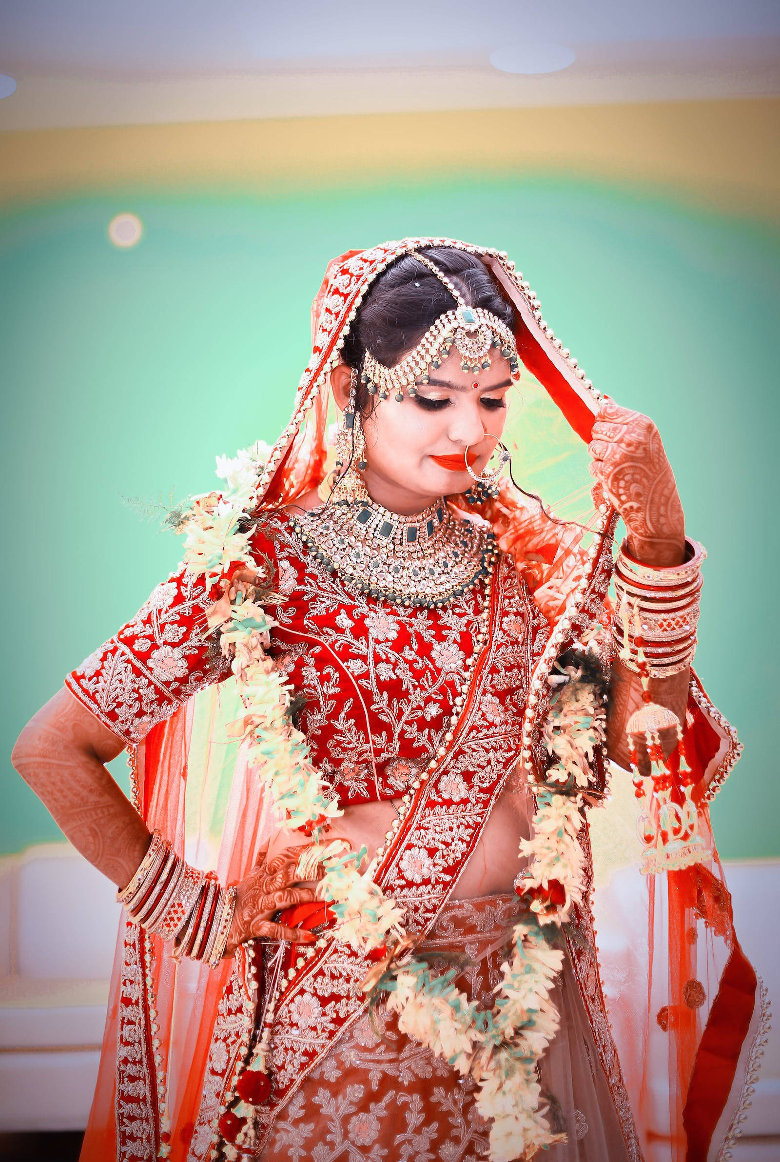 Indian 桌布 壁紙 — 一位光彩照人的新娘，身穿華麗的紅色和金色傳統服飾，飾以花環和精緻珠寶，優雅地擺出姿勢。