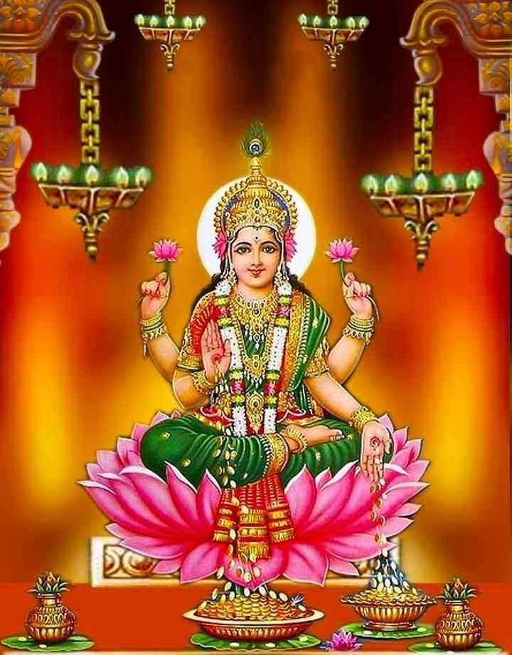 Lakshmi Devi 桌布 壁紙 — 一位光芒四射的印度教女神，擁有四臂，優雅地坐在粉紅色蓮花上，飾有黃金珠寶和花環，背景溫暖而發光。