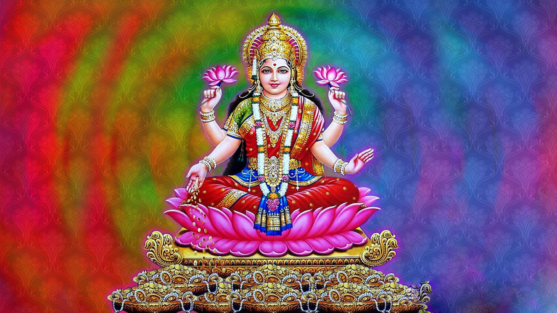 Indian 桌布 壁紙 — 一位光芒四射的印度教女神，有四隻手臂，優雅地坐在粉紅色蓮花寶座上，手持粉紅色蓮花，佩戴金色珠寶，背景是旋轉的彩虹漸變色。