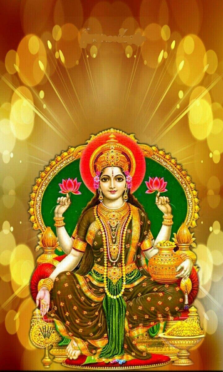 Lakshmi 桌布 壁紙 — 一位光芒四射的印度教女神，有多隻手臂，佩戴著黃金首飾，手持蓮花和一個壺，背景是閃爍的金色散景。