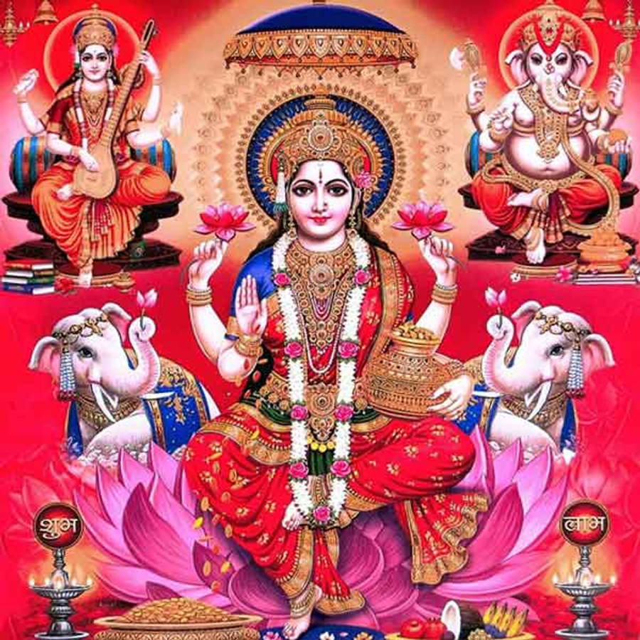 Lakshmi 桌布 壁紙 — 一位光芒四射的印度教女神坐在粉紅色蓮花上，兩旁有大象和神聖人物，身穿華麗的紅、金、藍色服飾。