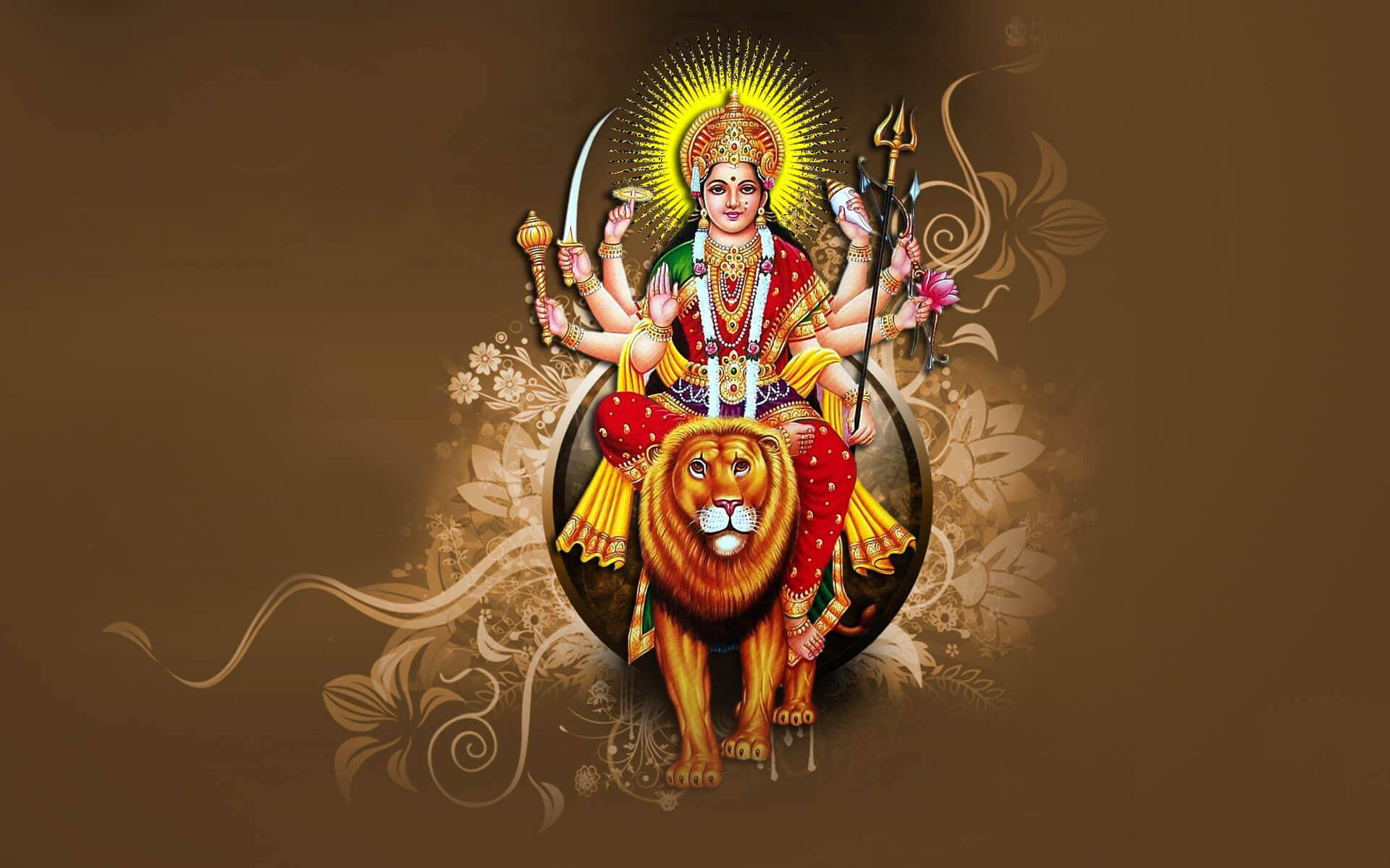 Indian 桌布 壁紙 — 一位光芒四射的多臂印度教女神騎著一頭雄偉的金獅，背景是帶有花卉漩渦的濃郁棕色。