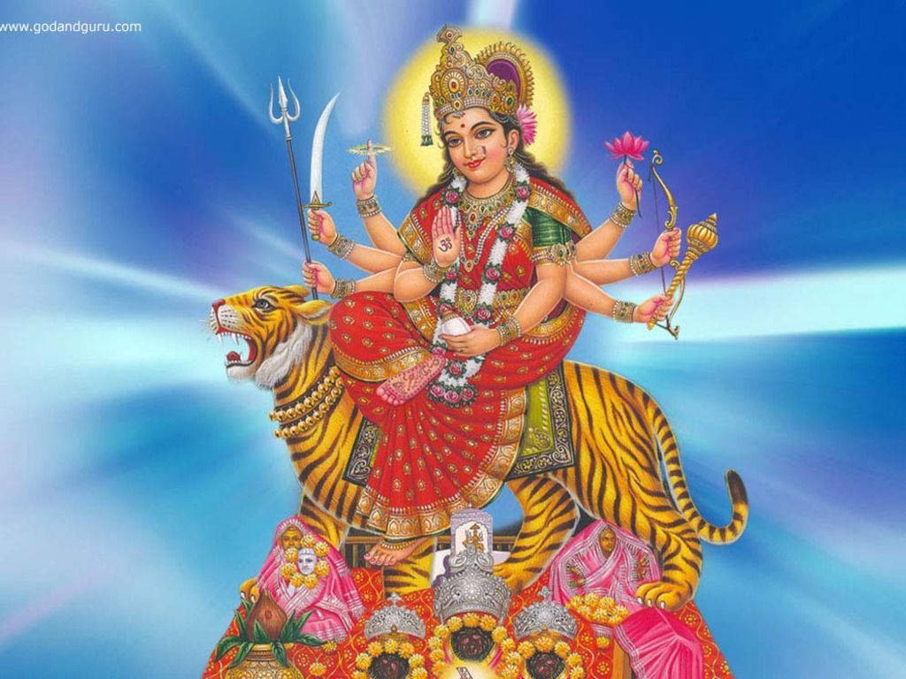 神 桌布 壁紙 — 一位光芒四射的多臂印度教女神騎著一頭兇猛的老虎，背景是發光的藍天和耀眼的光束。