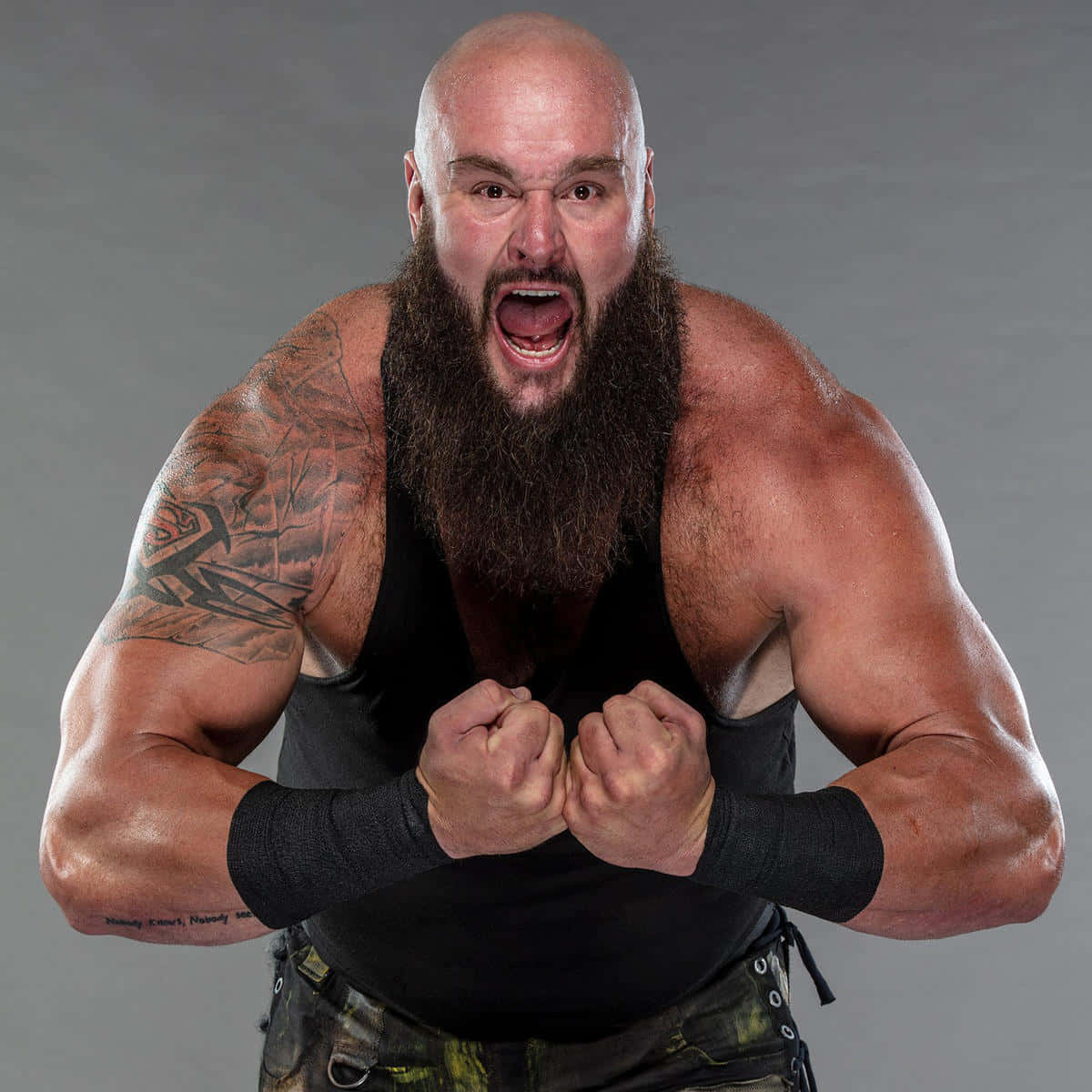 WWE 桌布 壁紙 — 一位光頭、留鬍子、有刺青的摔角手在攝影棚拍攝中緊握拳頭，兇猛咆哮。