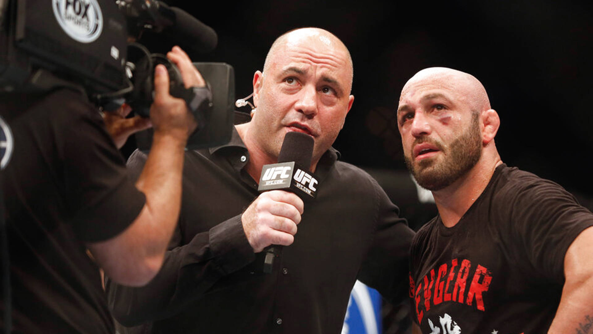 UFC 桌布 壁紙 — 一位光頭UFC拳手臉上帶傷，在明亮的場館燈光下，於賽後訪問中疲憊地坐著。