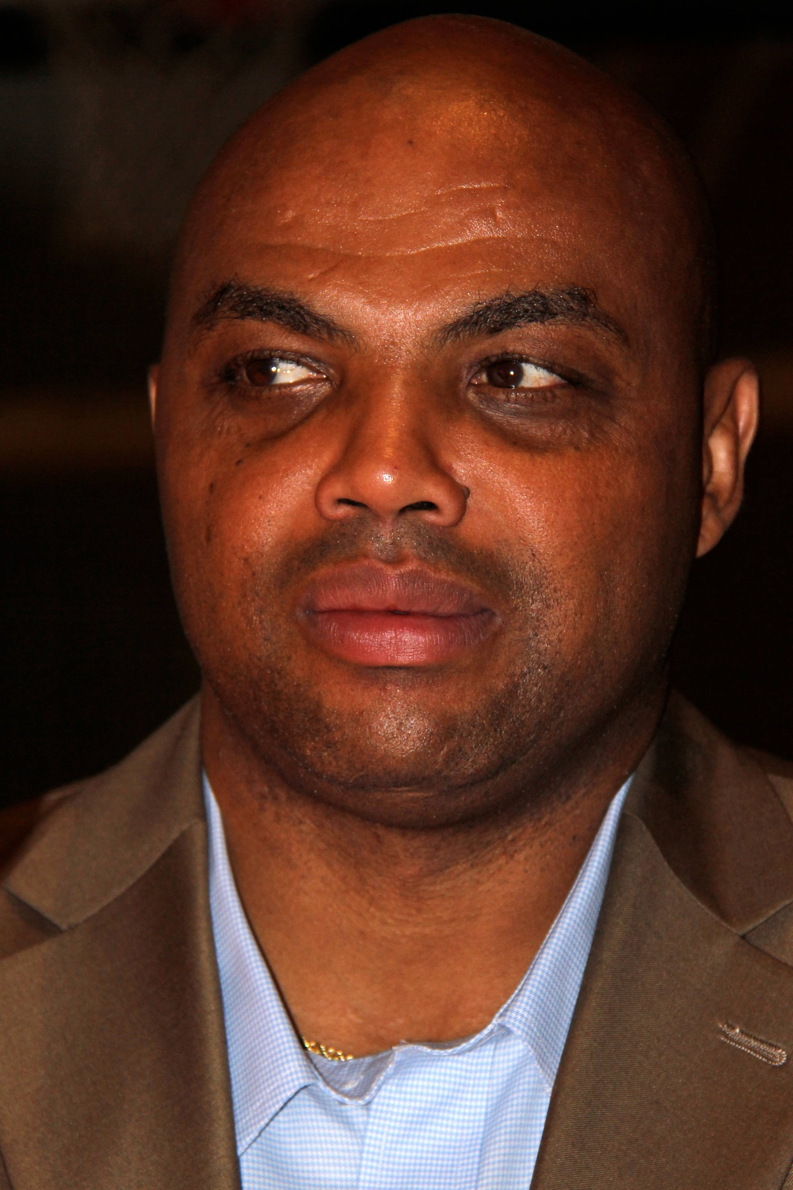 NBA 桌布 壁紙 — 一位光頭男士身穿棕色西裝和淺藍色襯衫，若有所思地望向一邊的特寫肖像。