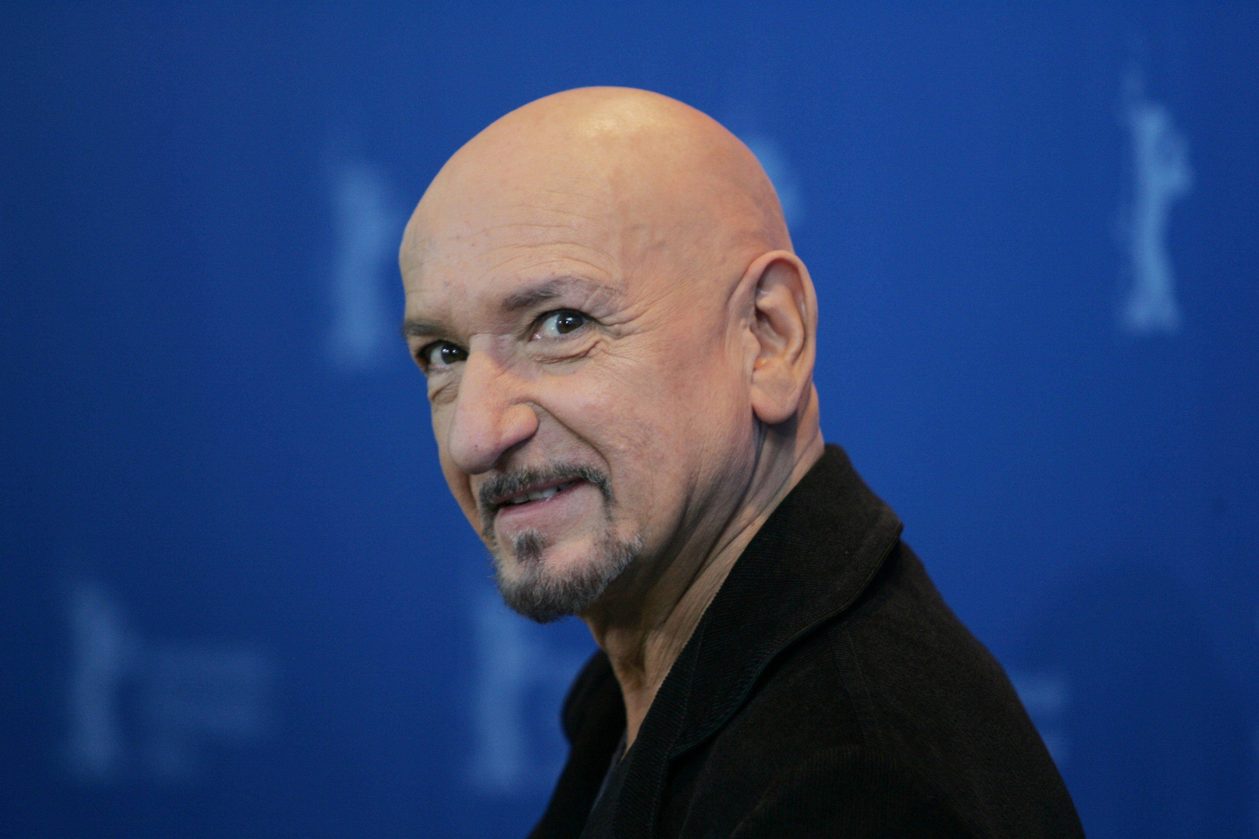 Celebrity 桌布 壁紙 — 一位光頭留山羊鬍的男人在純藍色背景上帶著模糊白色標誌微笑。