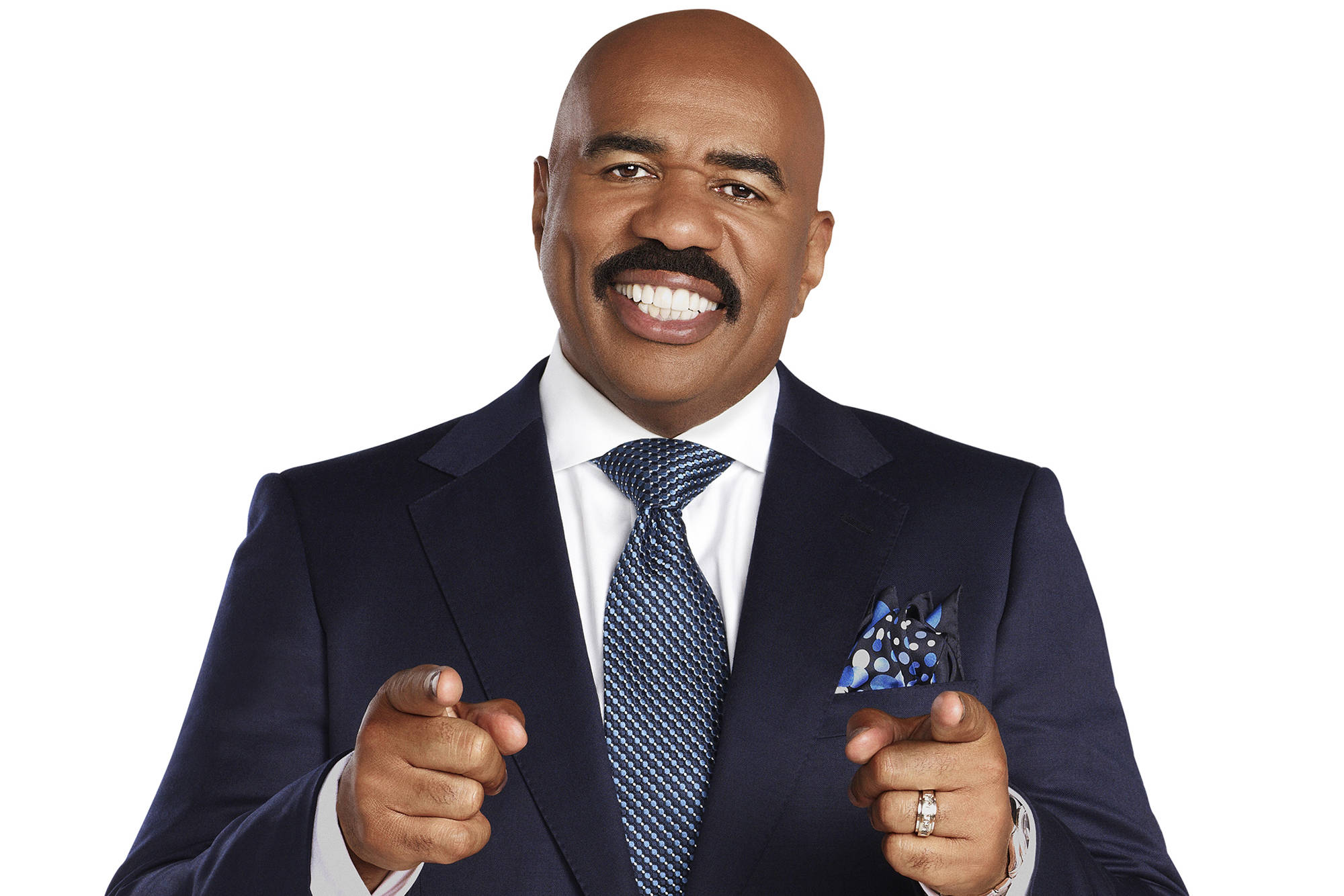 steve harvey 桌布 壁紙 — 一位光頭留鬍鬚的男人身穿海軍藍西裝，在白色背景前微笑著直接指向觀眾。