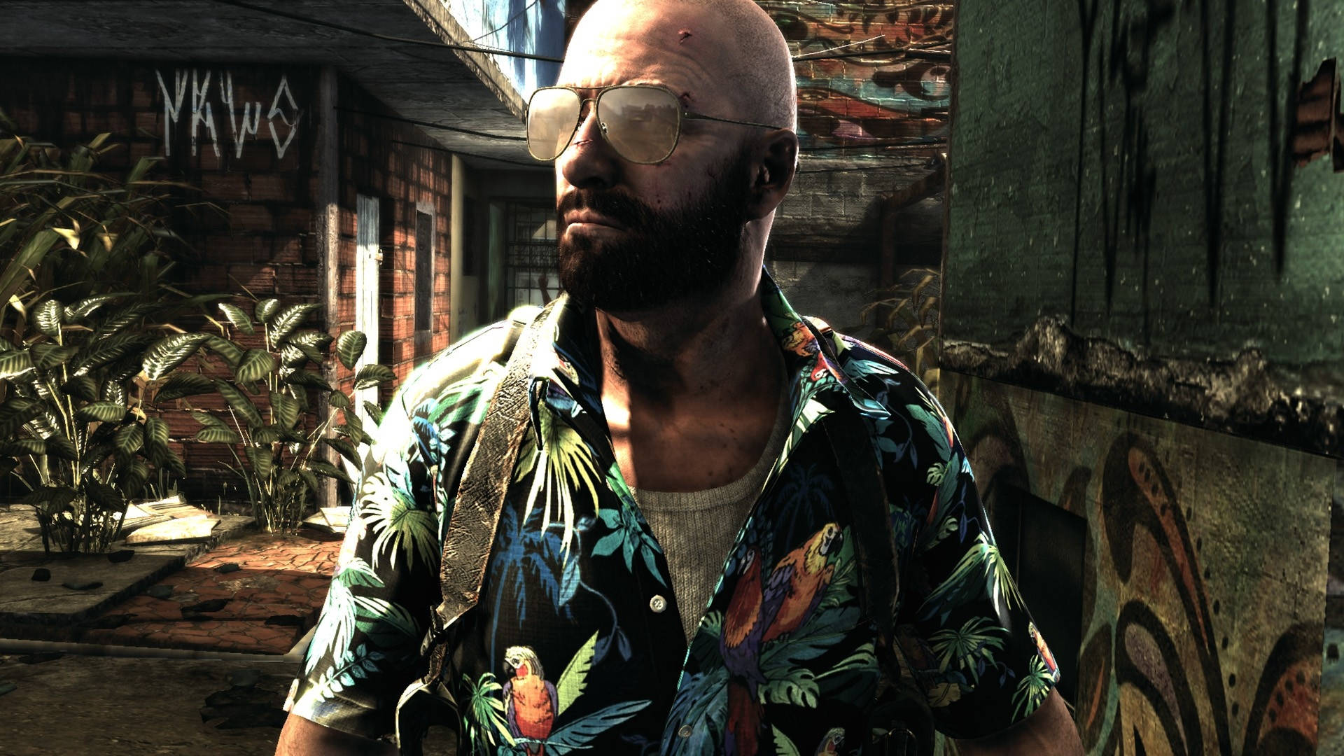 Max Payne 桌布 壁紙 — 一位光頭留鬍鬚的男子戴著飛行員太陽眼鏡，身穿熱帶印花襯衫，站在佈滿塗鴉的都市小巷中。
