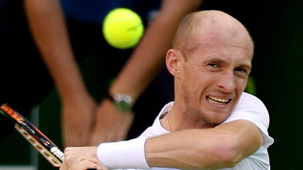 Tennis 桌布 壁紙 — 一位光頭網球運動員在揮拍擊打鮮黃色網球時，因極度專注而扭曲表情。