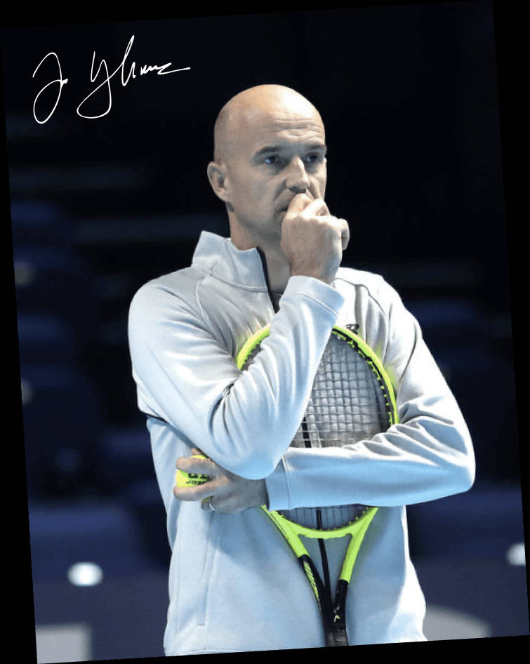 Tennis 桌布 壁紙 — 一位光頭網球選手身穿淺灰色夾克，手持螢光黃色球拍，拳頭托腮，若有所思，背景是黑暗模糊的球場。