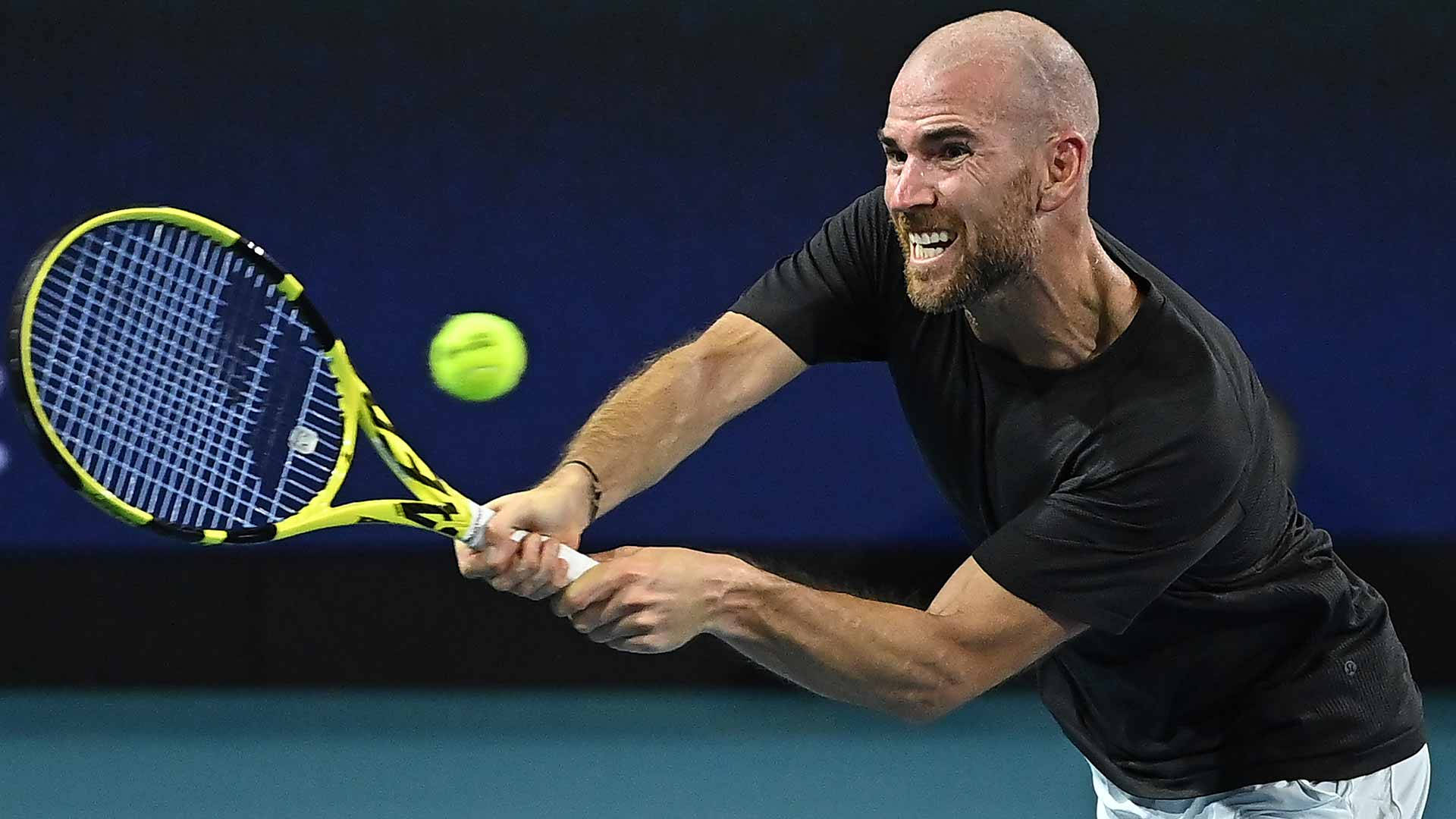Tennis 桌布 壁紙 — 一位光頭鬍鬚的網球運動員在揮動黃色球拍擊打亮綠色球時，表情極度猙獰。