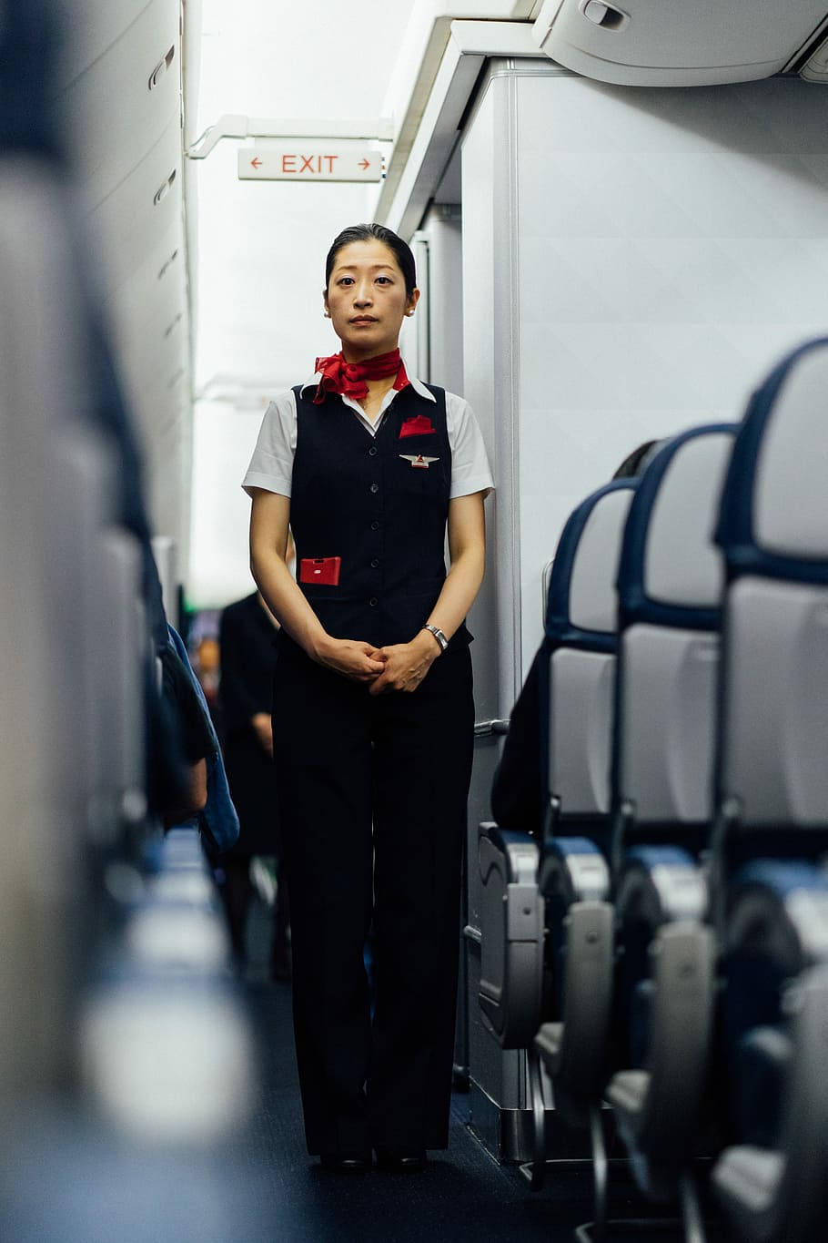 Airport 桌布 壁紙 — 一位冷靜的女空服員在飛機走道中，座位排之間，在柔和的機艙燈光下優雅地站立。