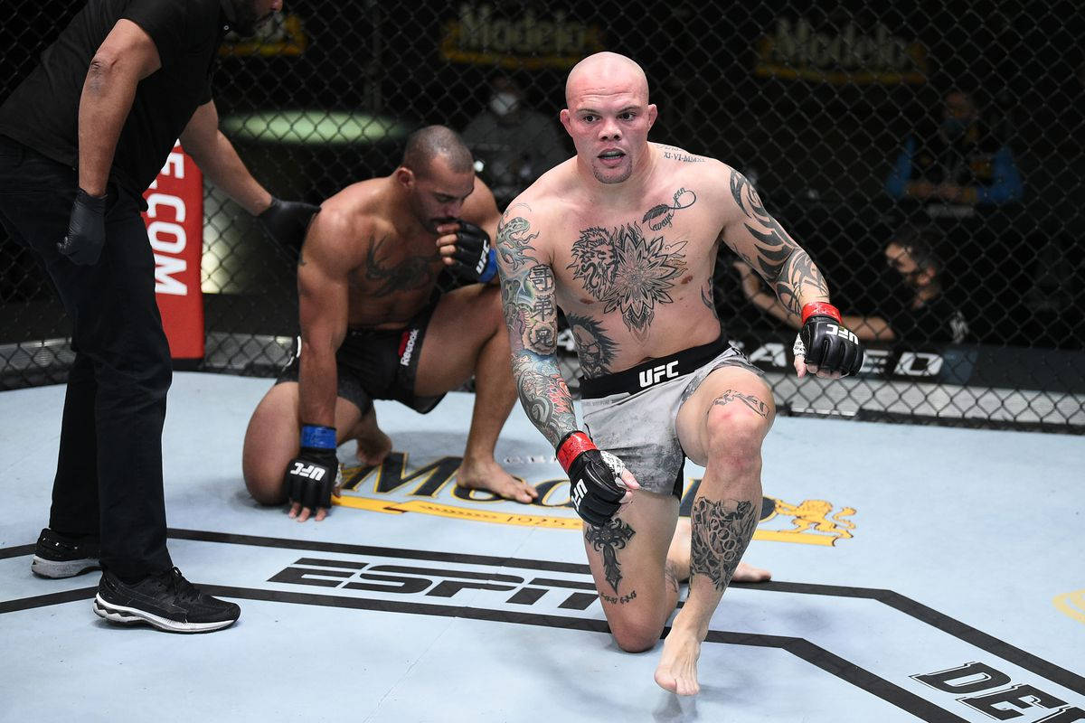 MMA 桌布 壁紙 — 一位刺青MMA拳手在八角籠中跪地勝利，對手在墊上投降。