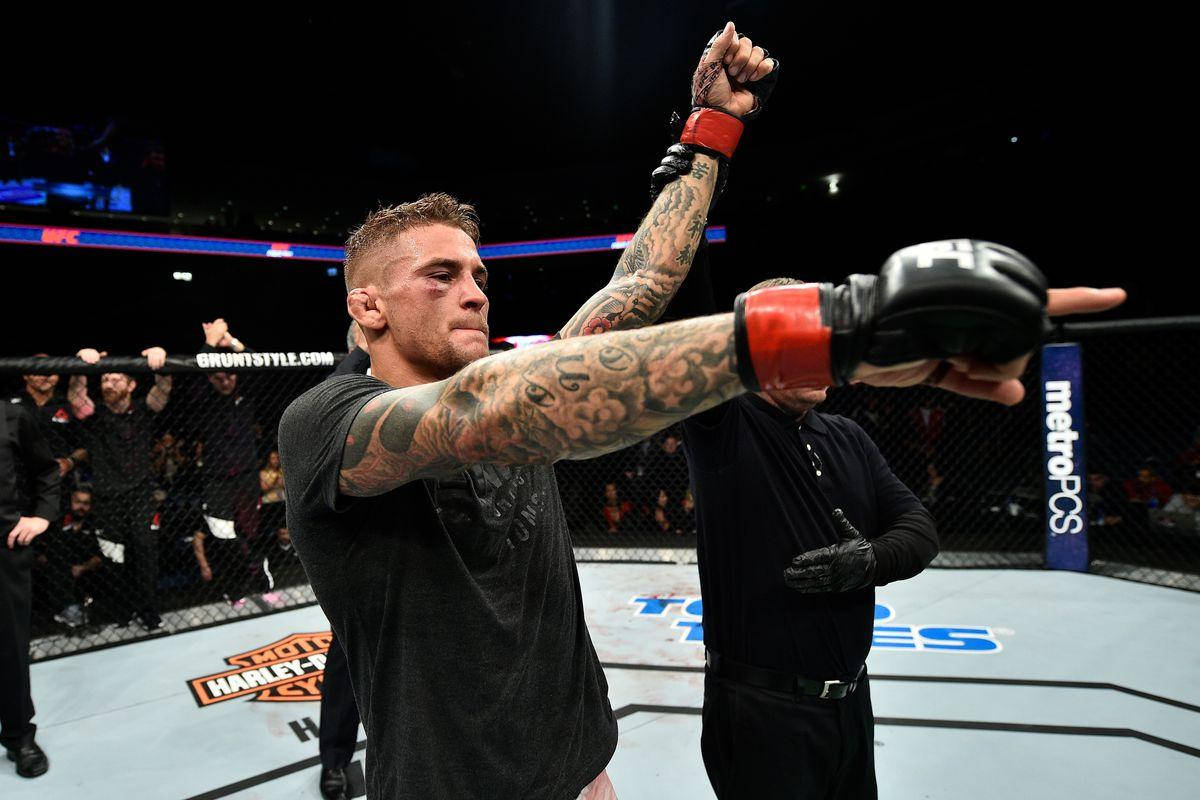 UFC 桌布 壁紙 — 一位刺青戰士在燈光明亮的八角籠中勝利地舉起戴著手套的拳頭，裁判站在他旁邊。