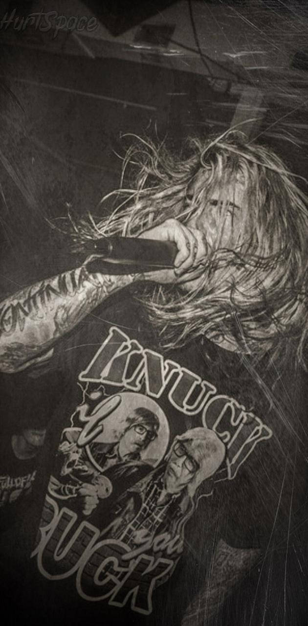 Ghostemane 桌布 壁紙 — 一位刺青音樂人頭髮狂野，穿著圖案T恤，在黑白粗獷的演唱會鏡頭中對著麥克風嘶吼。