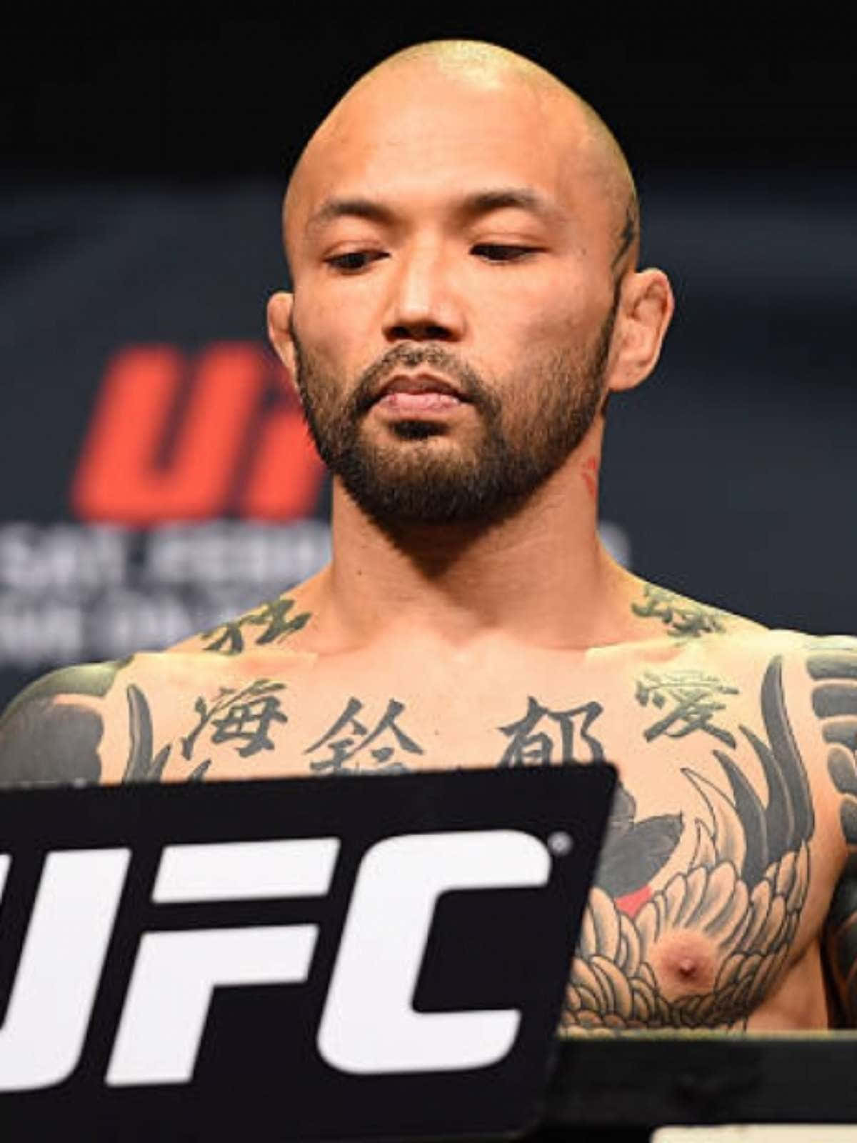 UFC 桌布 壁紙 — 一位剃光頭、留鬍子、有刺青的UFC拳手莊嚴地站在稱重台上。