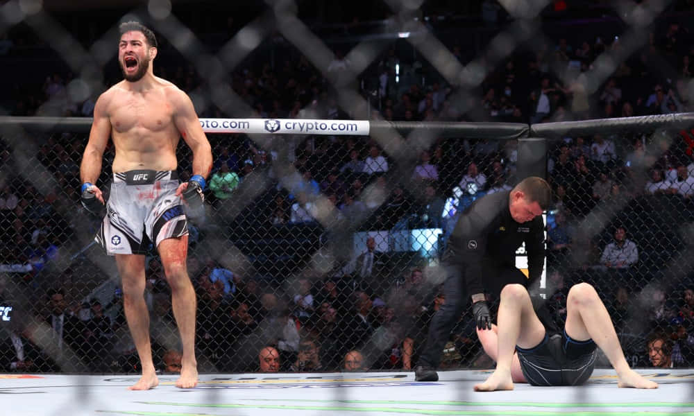 UFC 桌布 壁紙 — 一位勝利的MMA拳手在八角籠內咆哮歡呼，而他的對手則癱倒落敗。