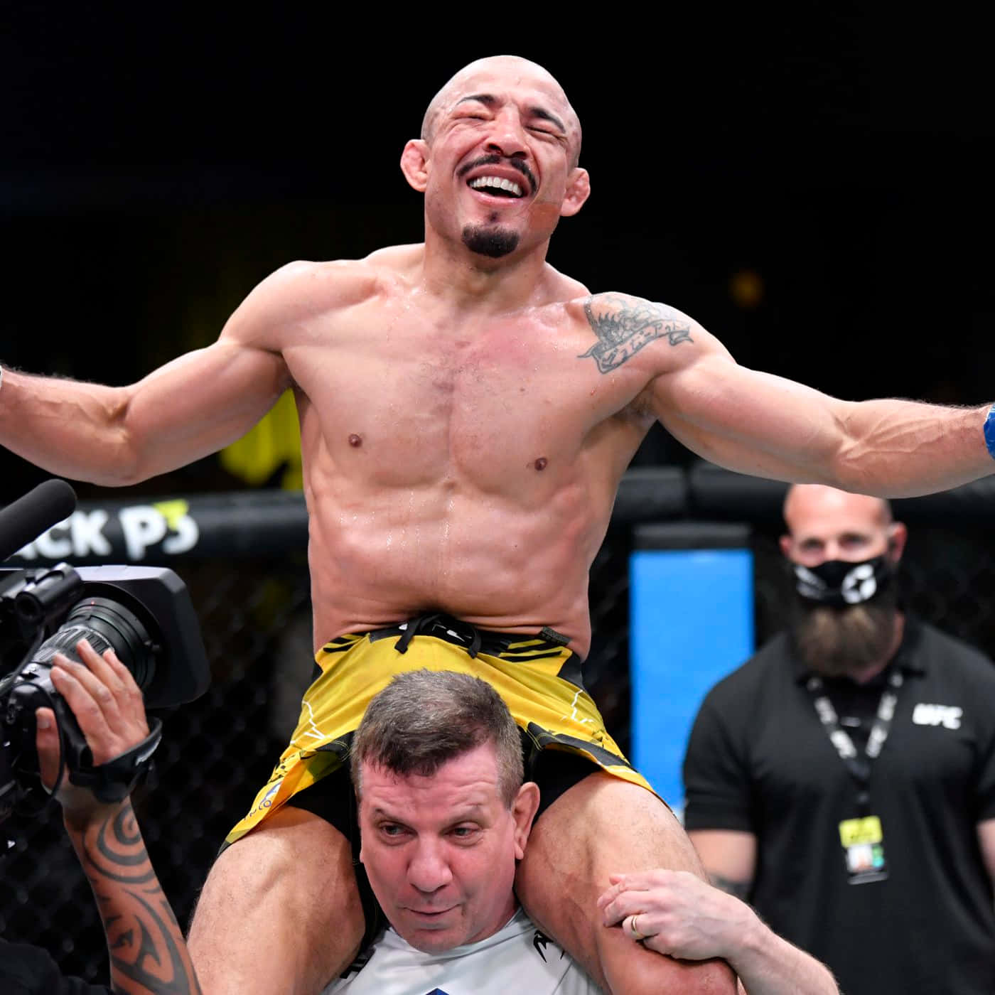 UFC 桌布 壁紙 — 一位勝利的MMA拳手在八角籠內被教練扛在肩上，開懷大笑。