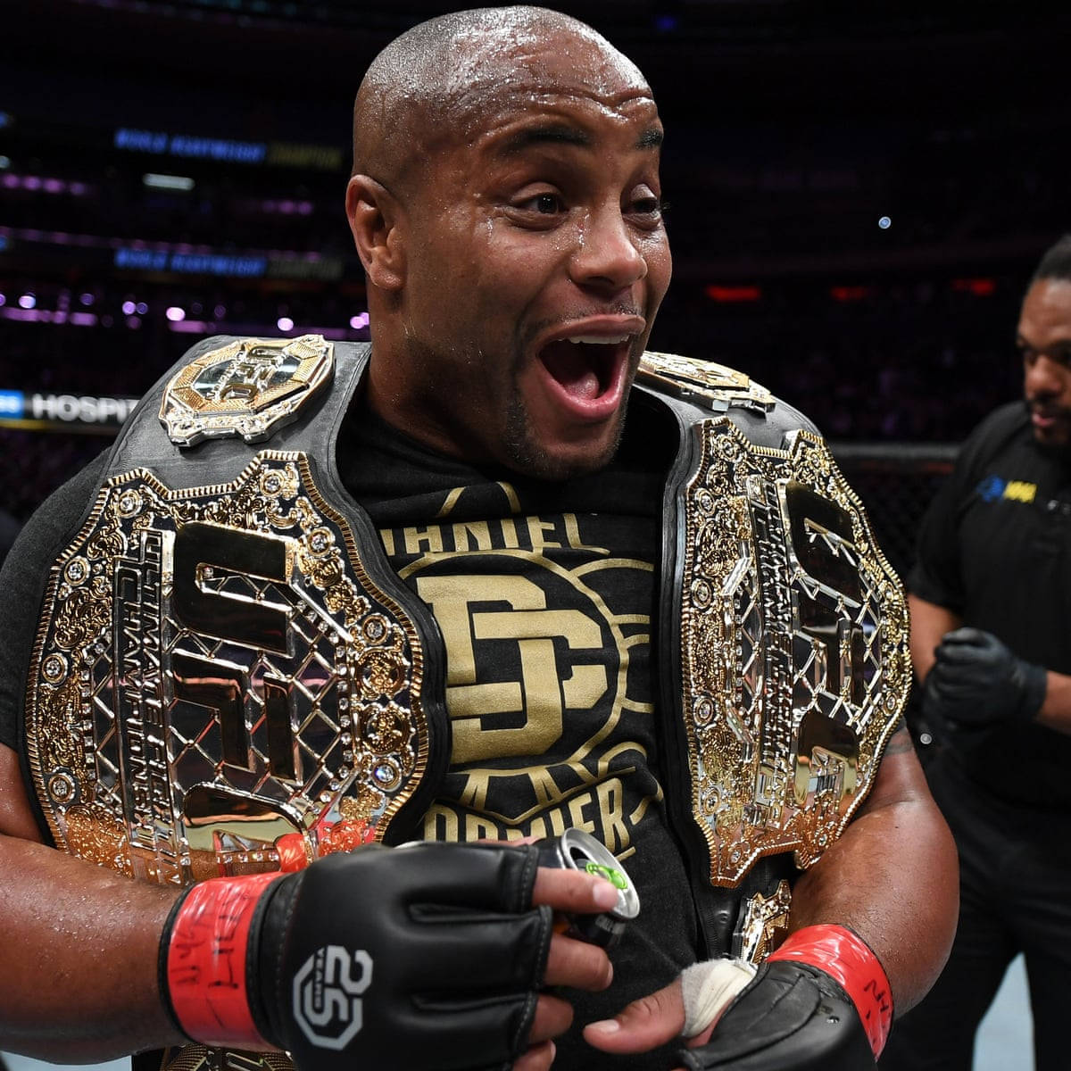 Champion 桌布 壁紙 — 一位勝利的MMA拳手在燈光明亮的競技場中，肩上披著閃閃發光的冠軍腰帶慶祝勝利。