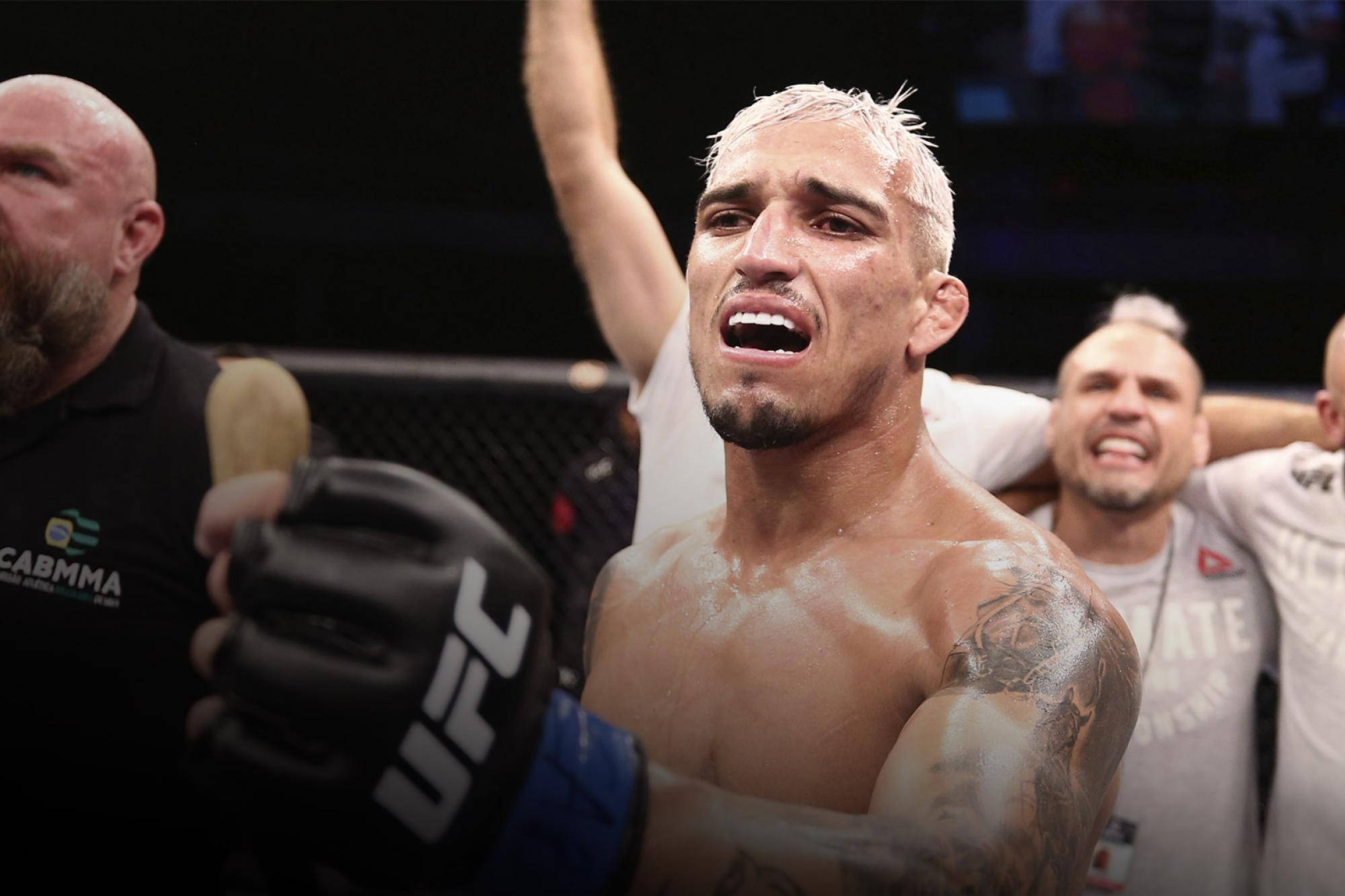 MMA 桌布 壁紙 — 一位勝利的UFC拳手，漂染頭髮和刺青，在八角籠內咆哮勝利，他的團隊在他身後慶祝。