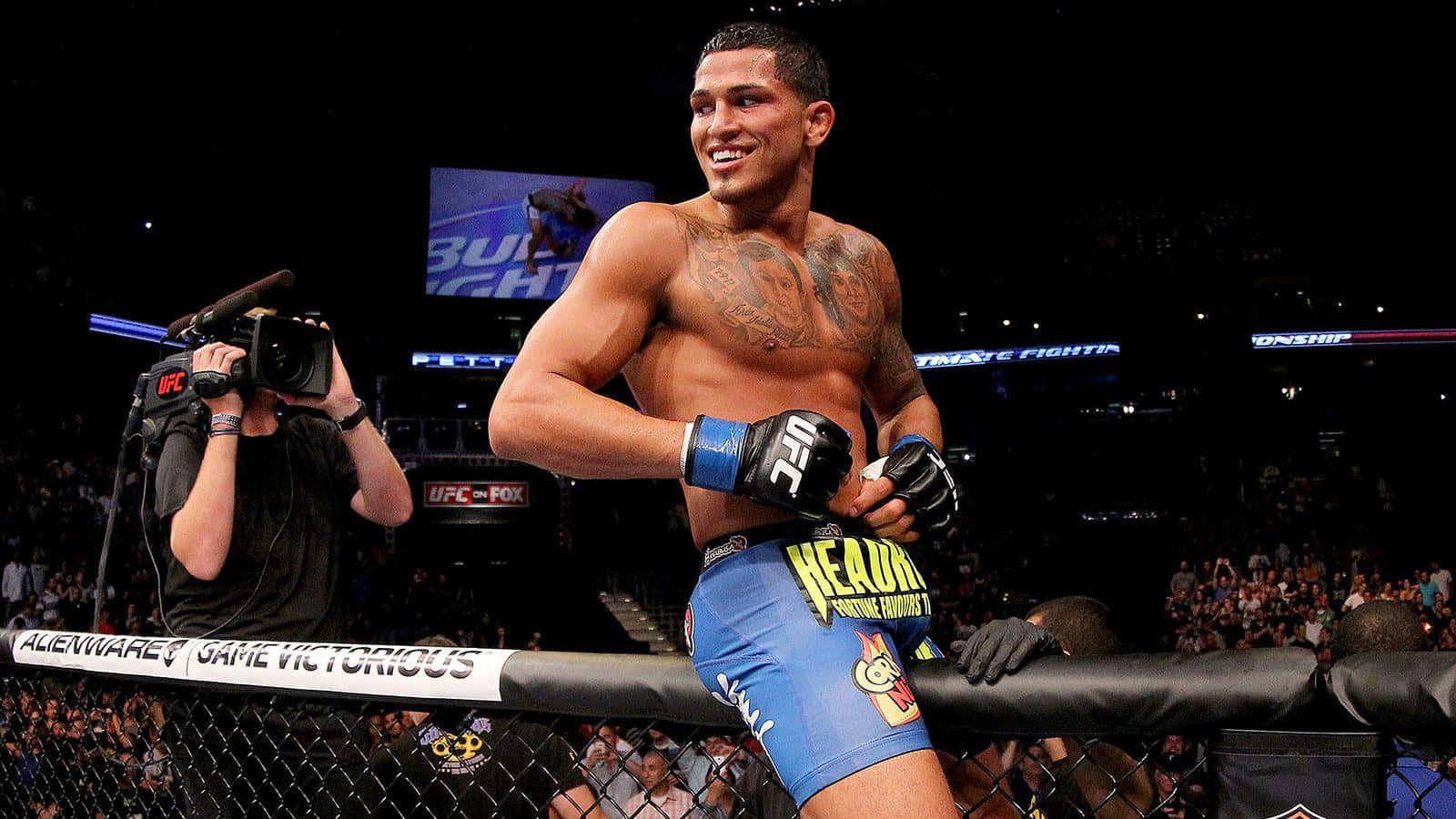 UFC 桌布 壁紙 — 一位勝利的UFC拳手在八角籠中自信微笑，背景有群眾和相機。