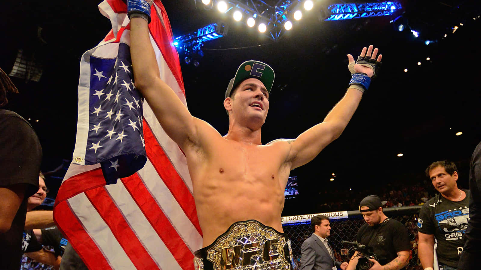 Flag 桌布 壁紙 — 一位勝利的UFC拳手在八角籠中舉著美國國旗和冠軍腰帶慶祝。