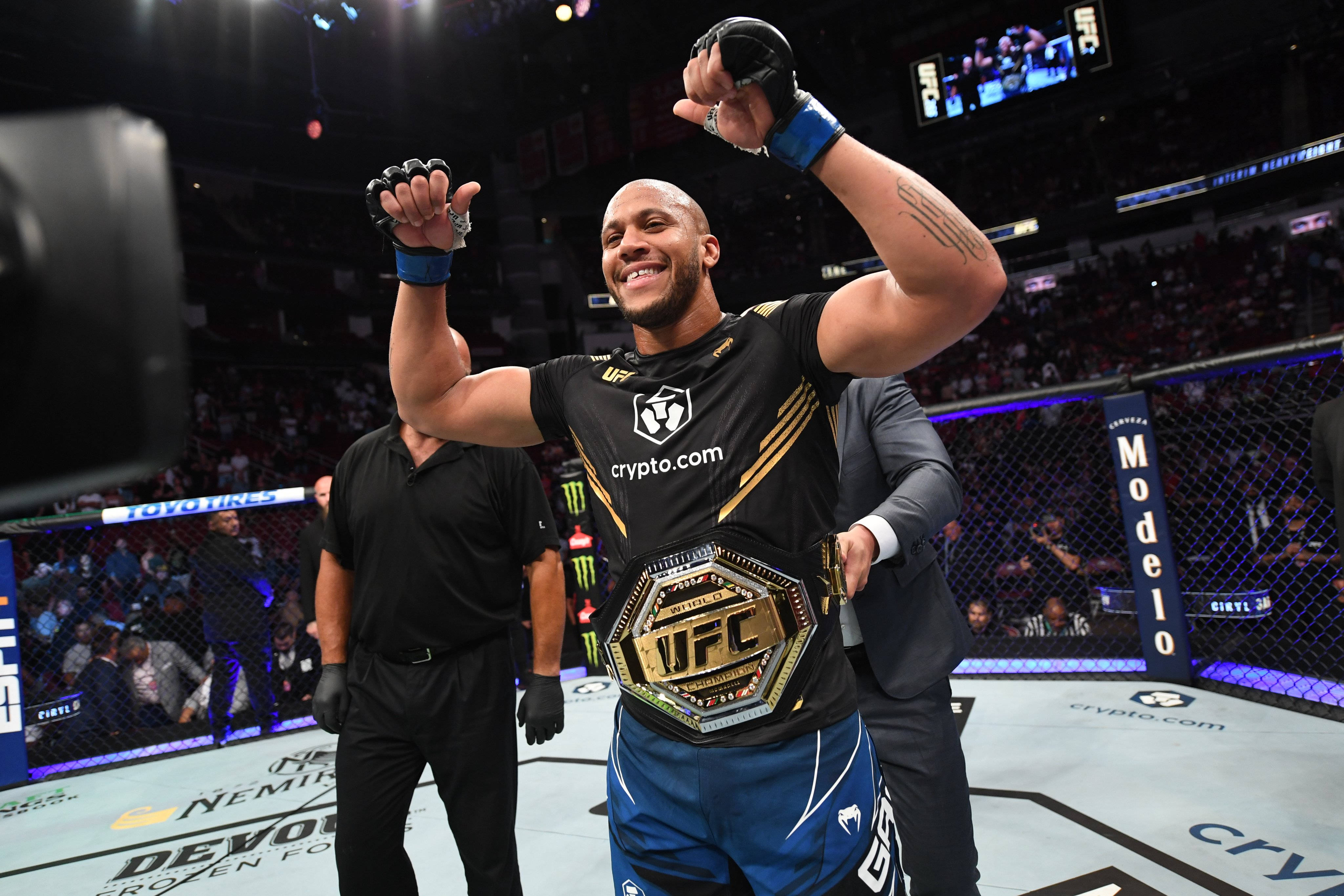 Victory 桌布 壁紙 — 一位勝利的UFC拳手在八角籠中高舉冠軍腰帶，在場館燈光下慶祝勝利。