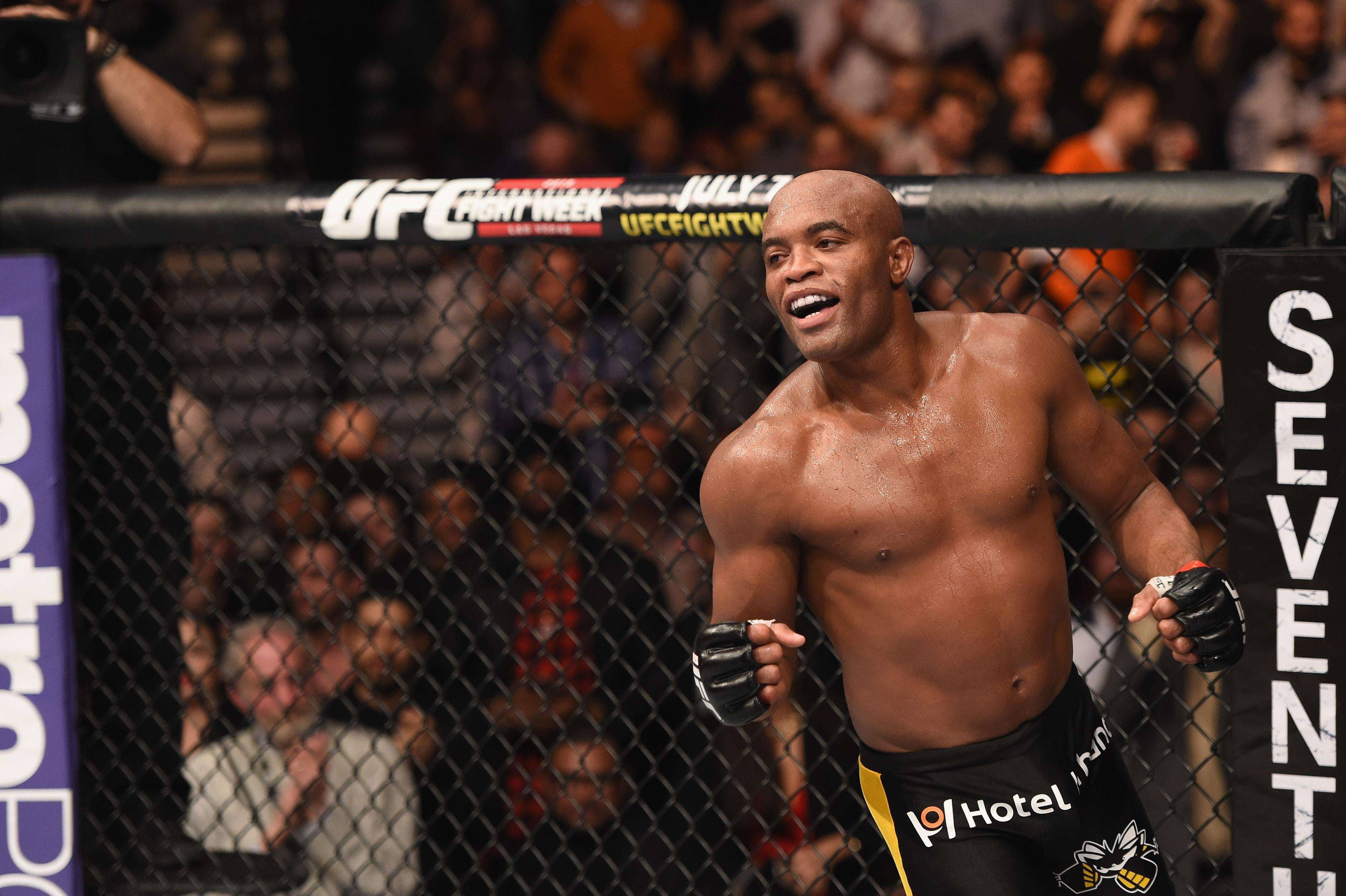 UFC 桌布 壁紙 — 一位勝利的UFC拳手在八角籠內咧嘴大笑，高舉拳頭慶祝勝利。