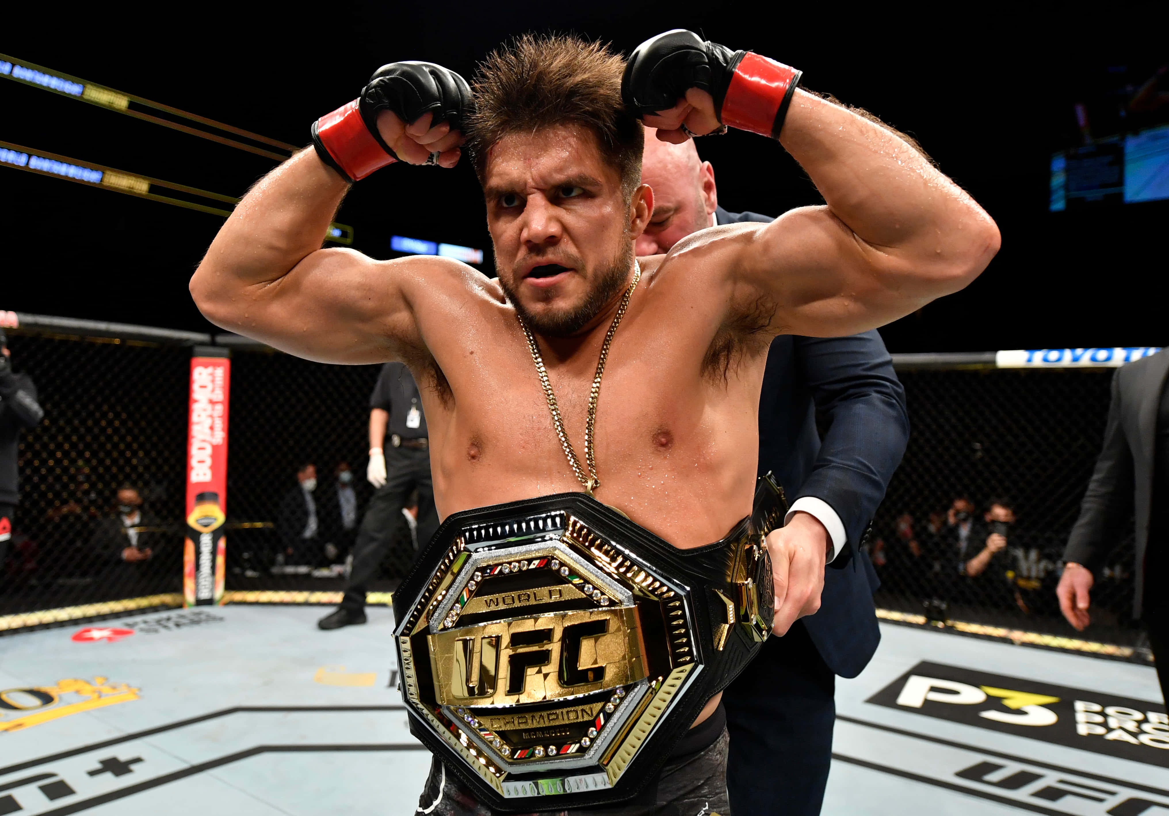 UFC 桌布 壁紙 — 一位勝利的UFC拳手在八角籠內展示肌肉，同時佩戴冠軍腰帶。