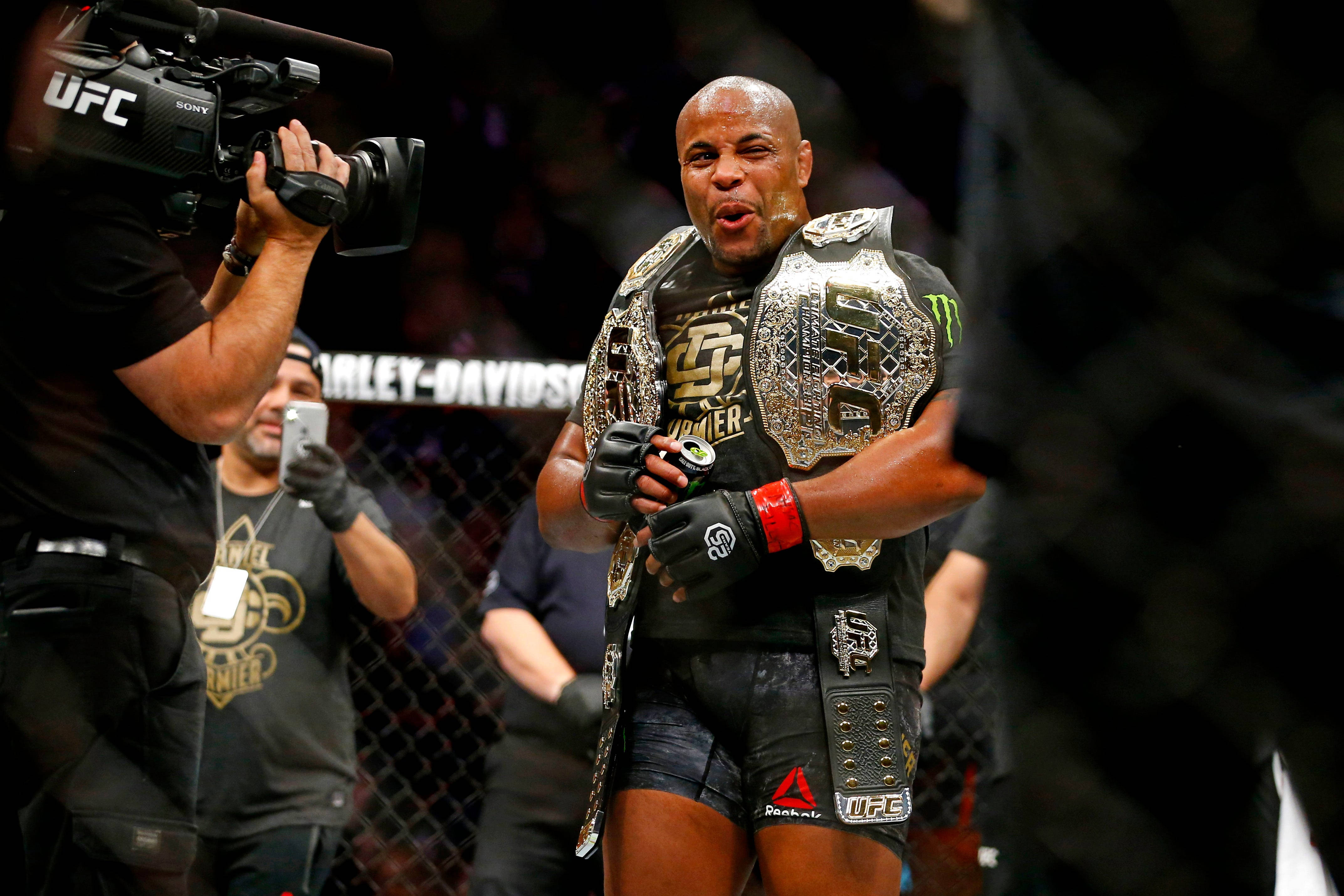Champion 桌布 壁紙 — 一位勝利的UFC拳手在八角籠內手持冠軍腰帶慶祝勝利。