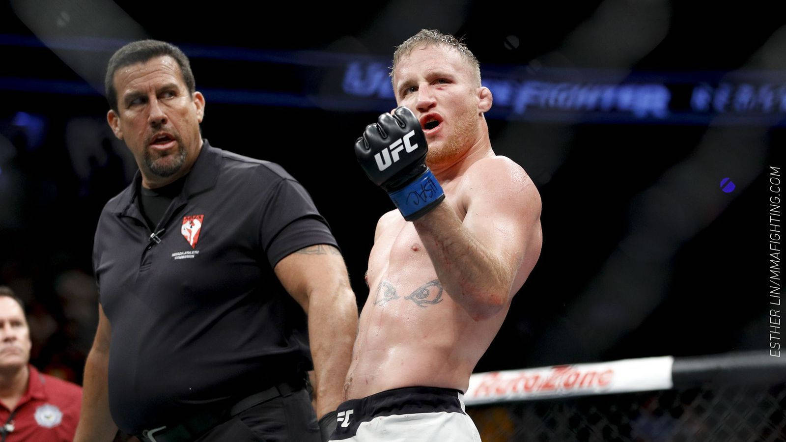快樂 桌布 壁紙 — 一位勝利的UFC拳手在八角籠內高舉戴著手套的拳頭慶祝勝利，裁判在旁近距離觀察。
