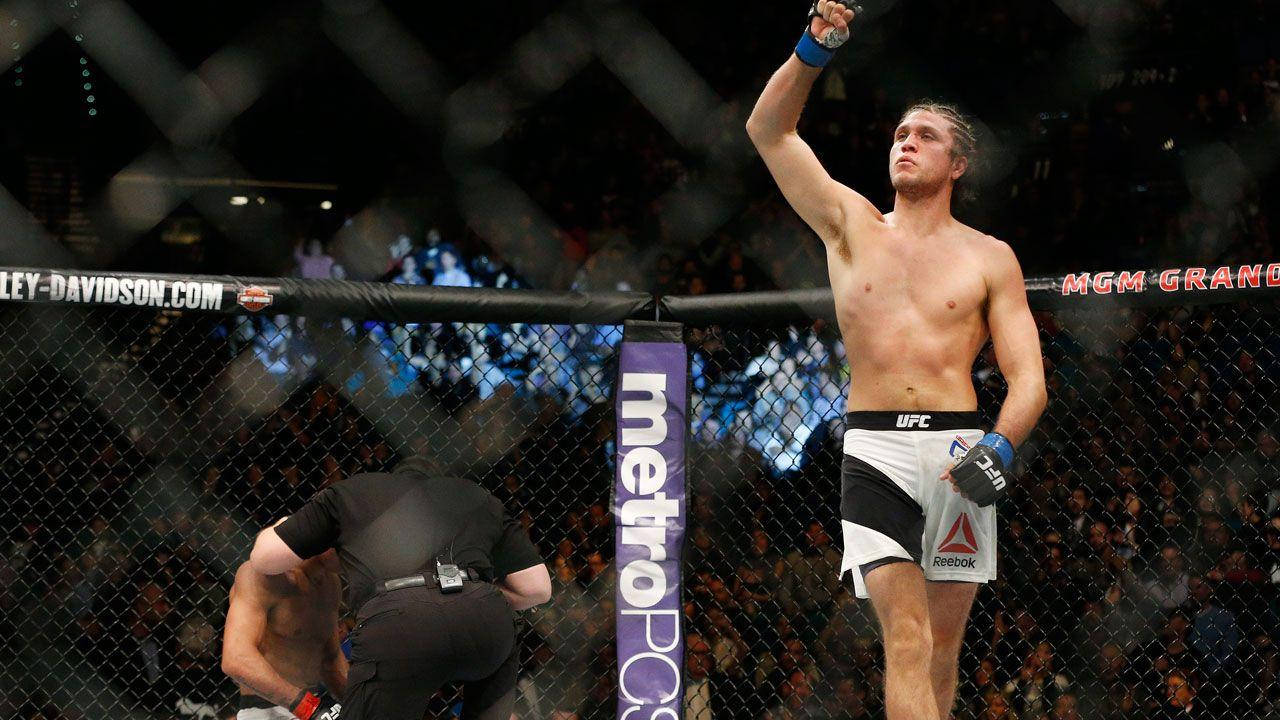 Brian Ortega 桌布 壁紙 — 一位勝利的UFC拳手在八角籠內高舉拳頭慶祝勝利，裁判正在照顧他的對手。