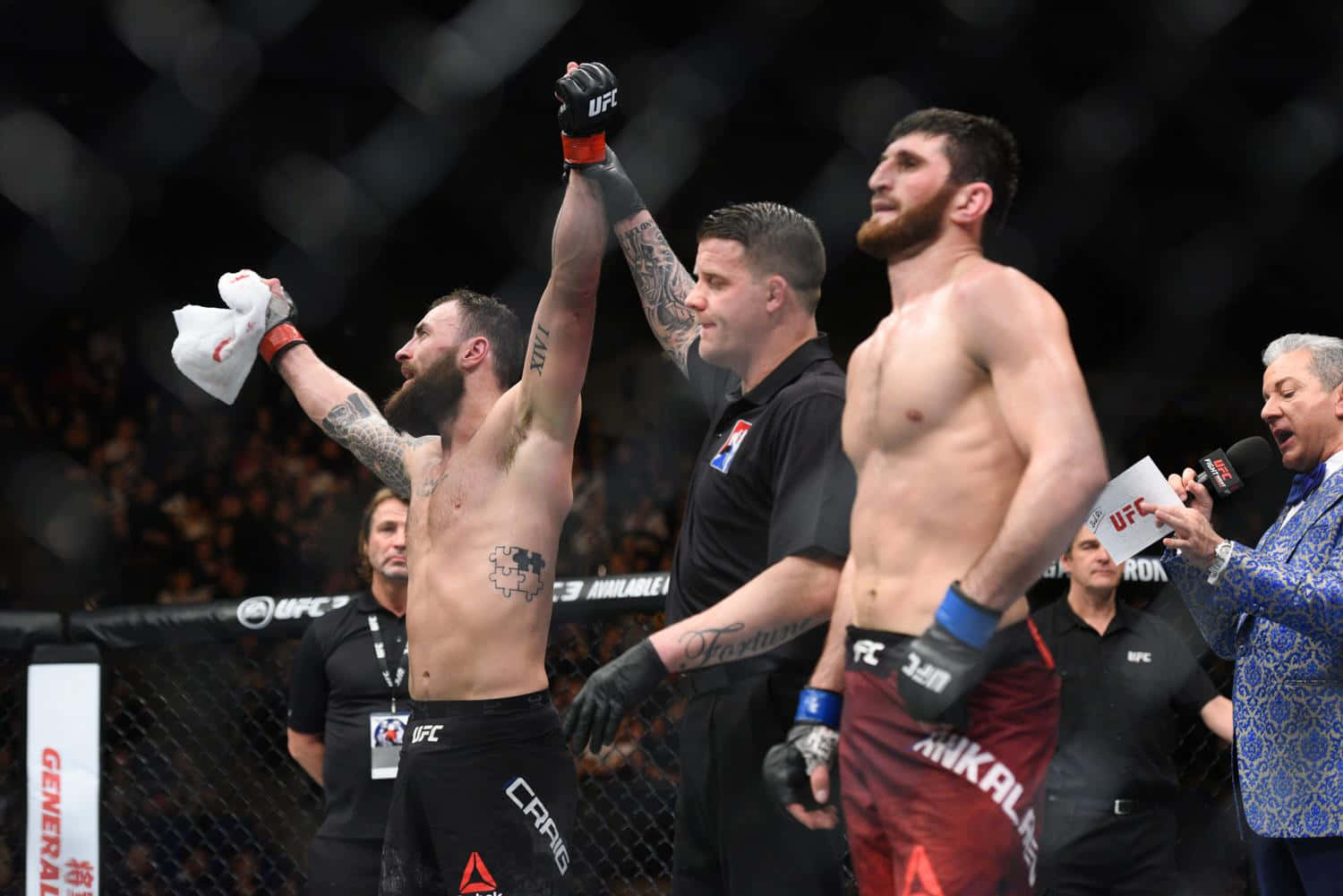 UFC 桌布 壁紙 — 一位勝利的UFC拳手在八角籠內高舉雙臂慶祝勝利，他的對手站在旁邊，裁判在旁觀看。