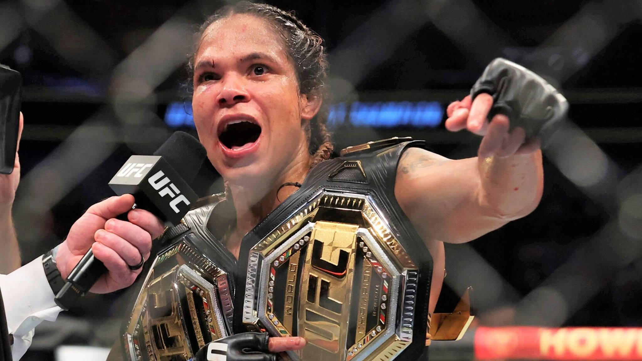 Champion 桌布 壁紙 — 一位勝利的UFC拳手在八角籠內高舉冠軍腰帶並握拳歡呼，喜極而泣。