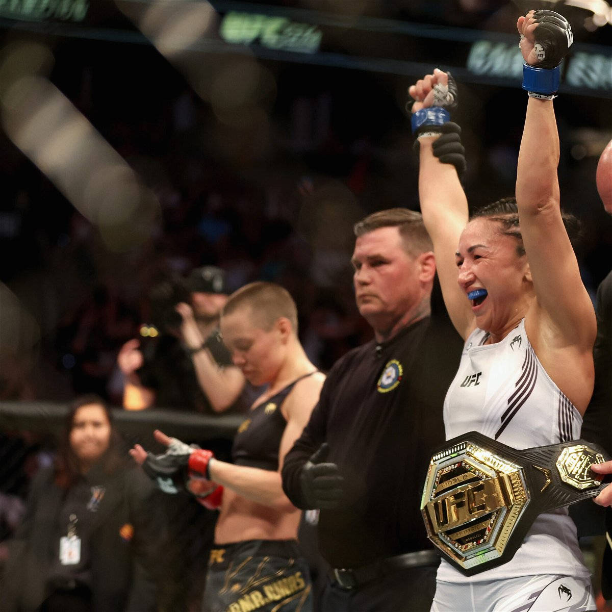 Champion 桌布 壁紙 — 一位勝利的UFC拳手在八角籠內高舉雙臂，手持冠軍腰帶慶祝。