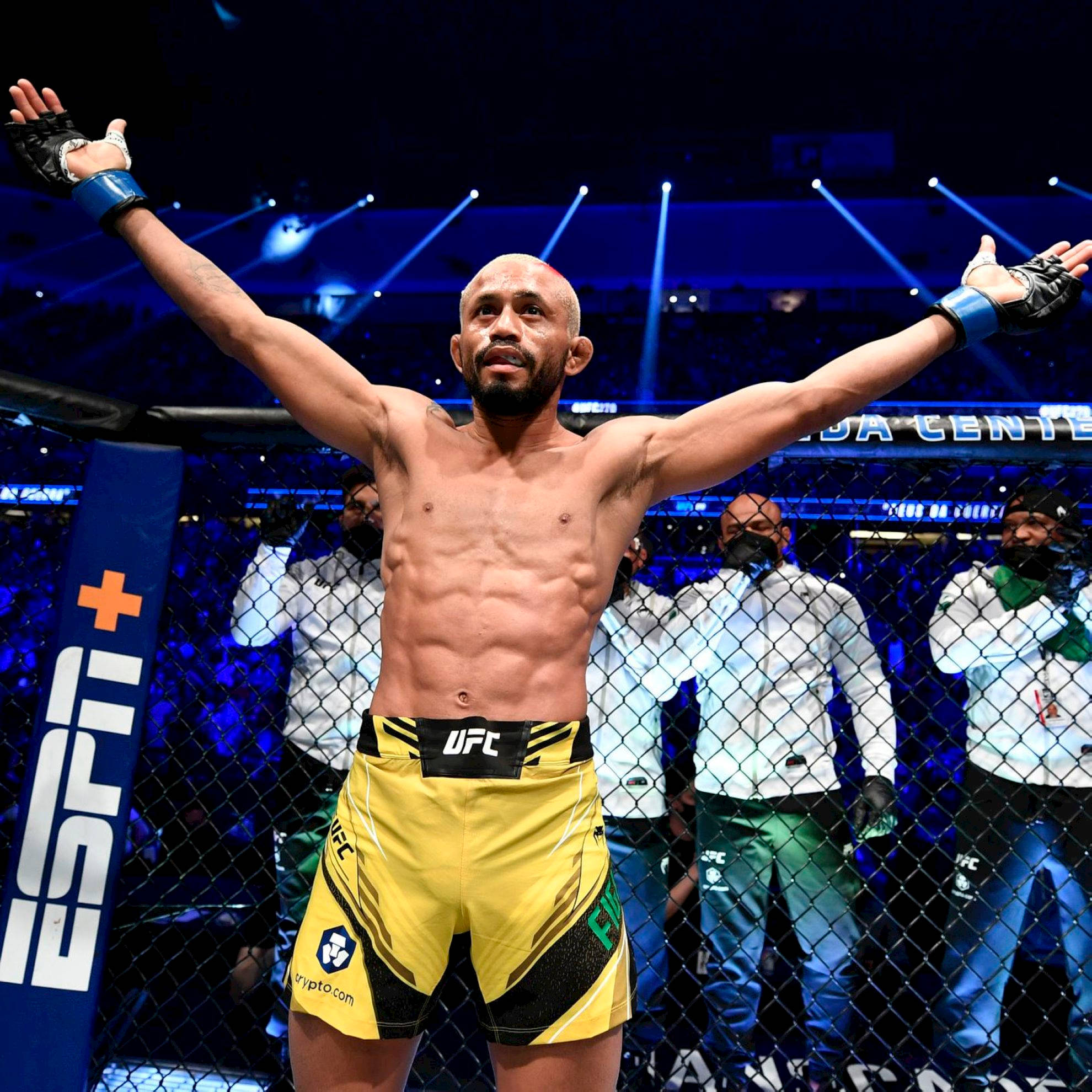 Victory 桌布 壁紙 — 一位勝利的UFC拳手在明亮的場館燈光下，於八角籠內高舉雙臂慶祝。