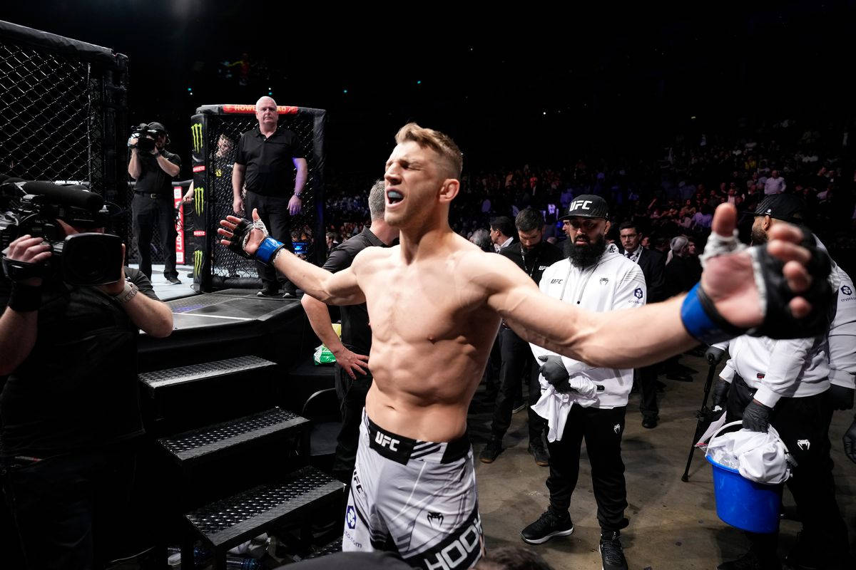 UFC 桌布 壁紙 — 一位勝利的UFC拳手在明亮的場館燈光下，比賽後張開雙臂慶祝。