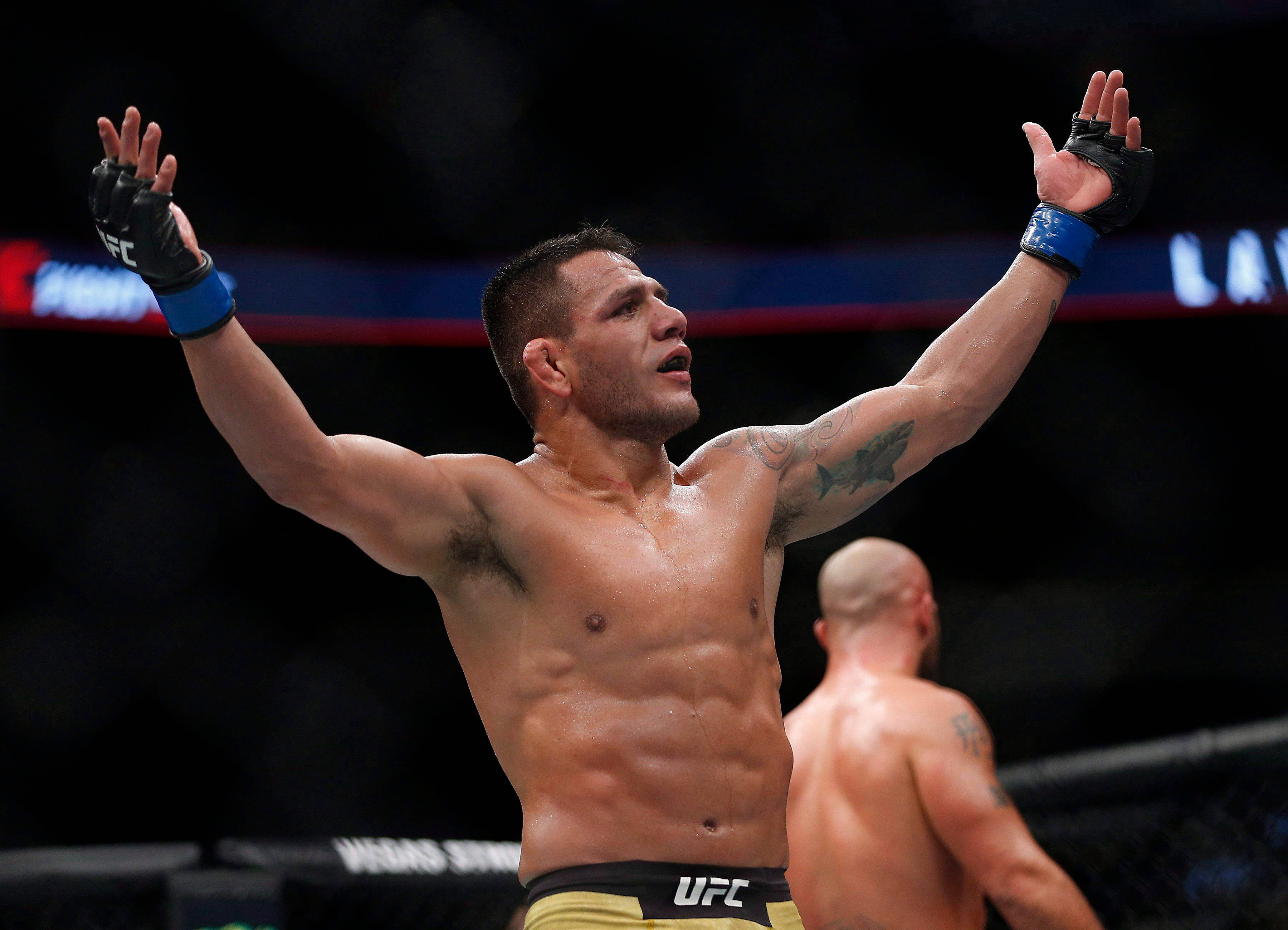 UFC 桌布 壁紙 — 一位勝利的UFC拳手在明亮的場館燈光下，於八角籠內高舉雙臂慶祝勝利。