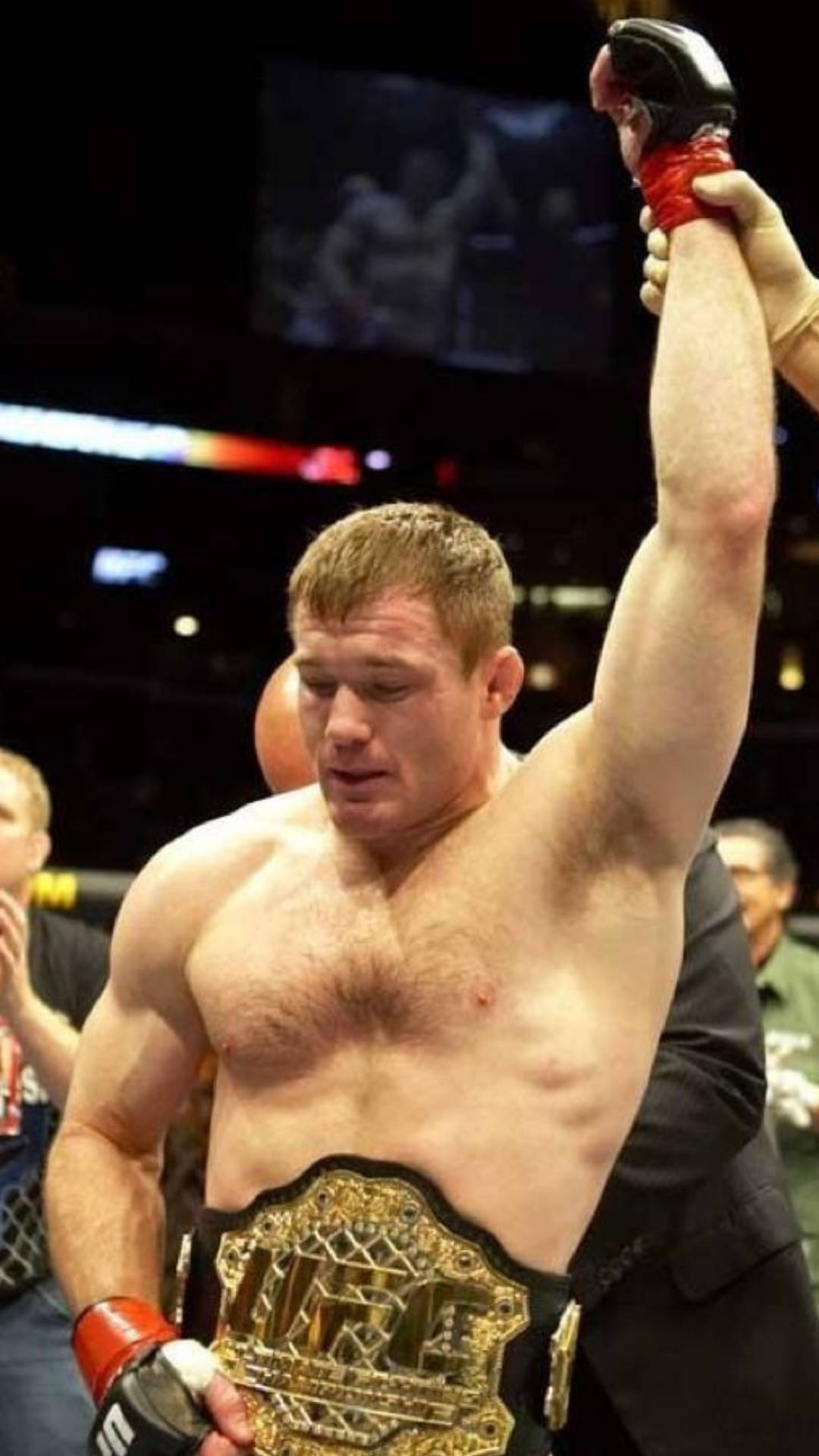 UFC 桌布 壁紙 — 一位勝利的UFC拳手帶著冠軍腰帶，在八角籠中被裁判舉起手臂。