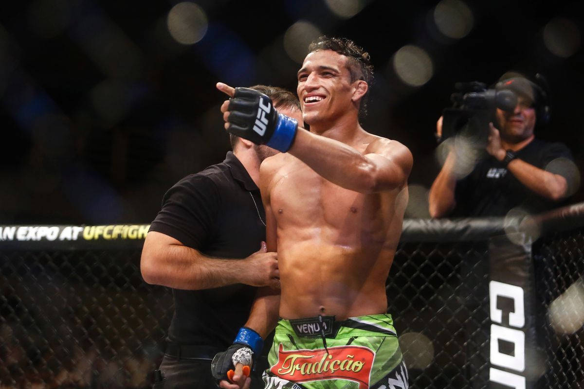 MMA 桌布 壁紙 — 一位勝利的UFC拳手滿面笑容，在八角籠內勝利地指著，裁判協助他。