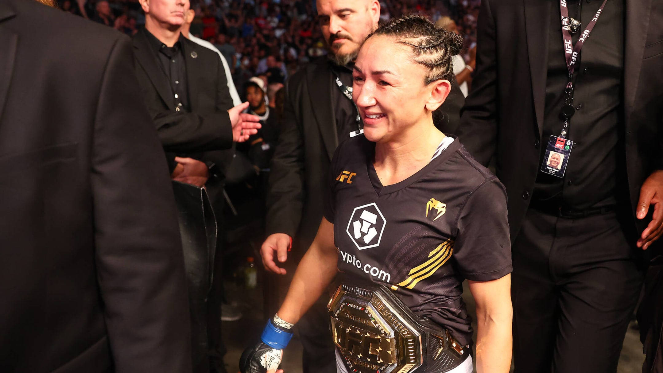 Champion 桌布 壁紙 — 一位勝利的女性UFC拳手在擠滿觀眾的場館中，自豪地展示她的冠軍腰帶，滿臉喜悅。