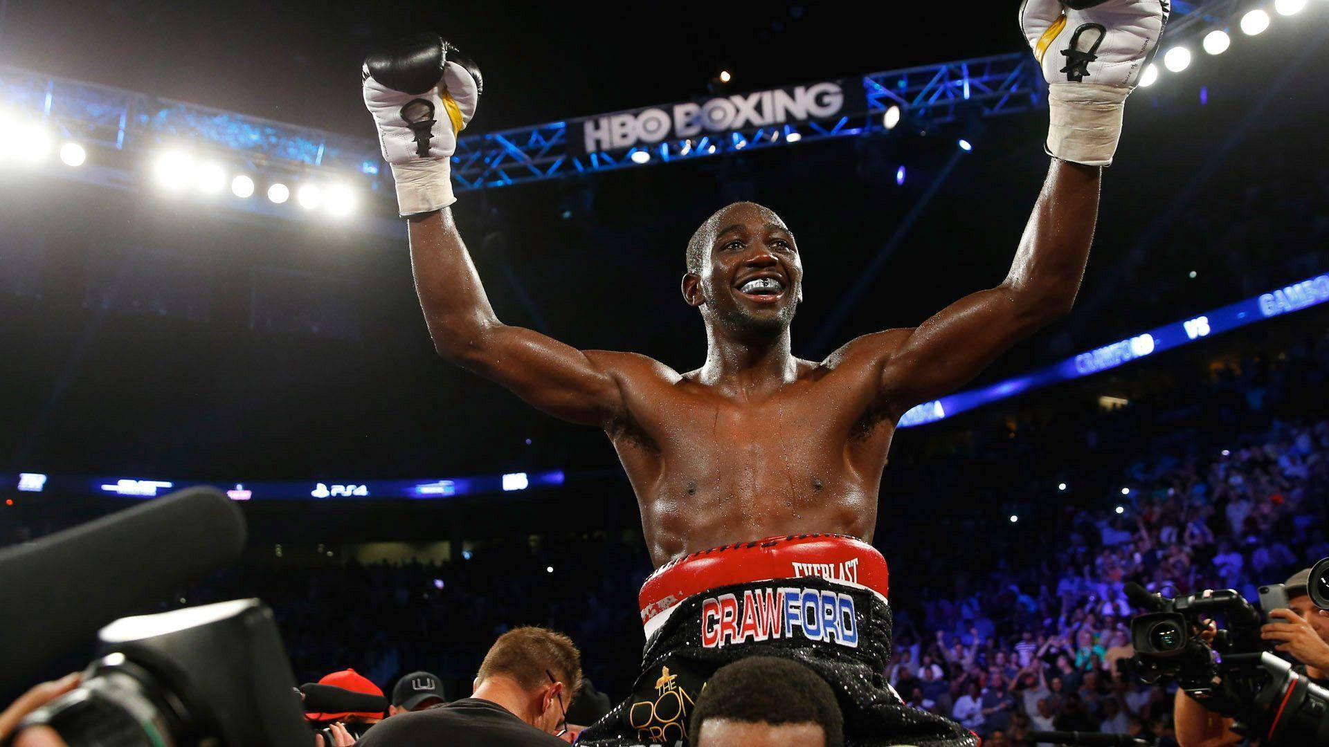 Boxing 桌布 壁紙 — 一位勝利的拳擊手在明亮的競技場燈光下，身後有歡呼的人群，舉起戴著手套的拳頭慶祝勝利。