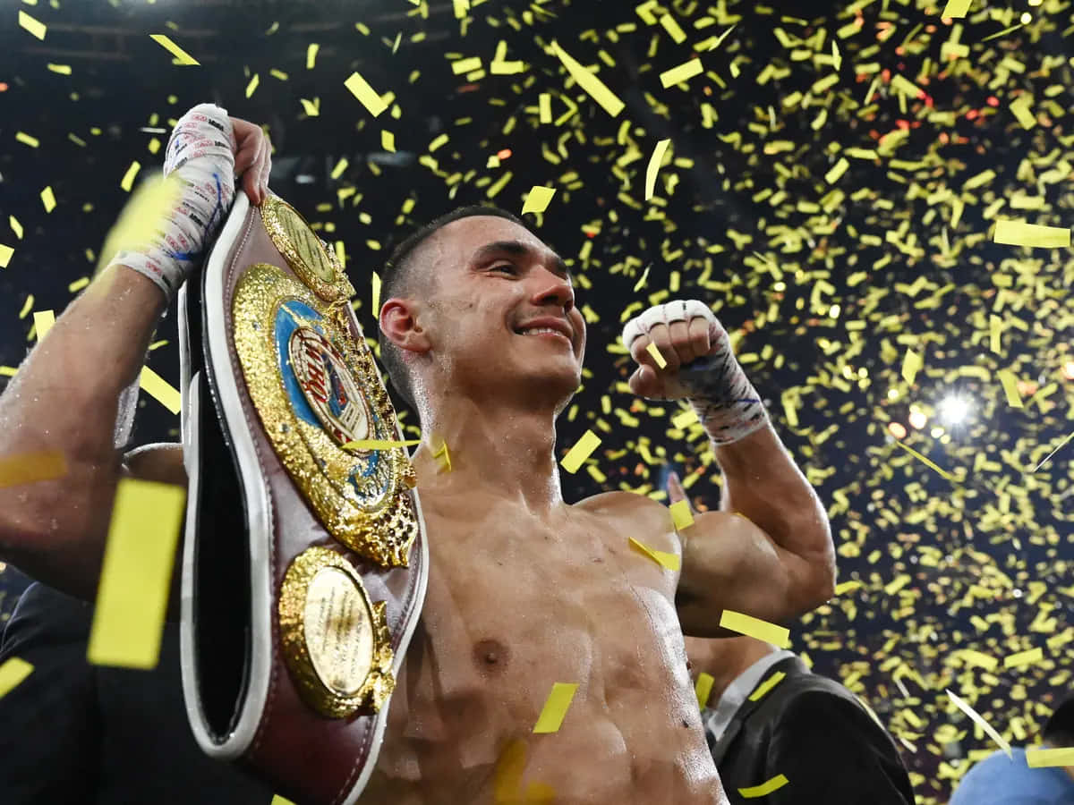 Tim Tszyu 桌布 壁紙 — 一位勝利的拳擊手高舉冠軍腰帶慶祝勝利，金色紙屑在他周圍飄落。
