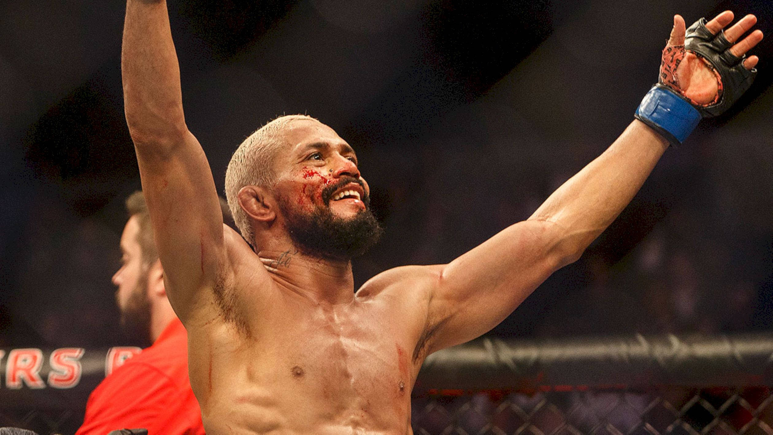 UFC 桌布 壁紙 — 一位勝利的混合武術家，滿臉鮮血，高舉雙臂，在籠內慶祝勝利。