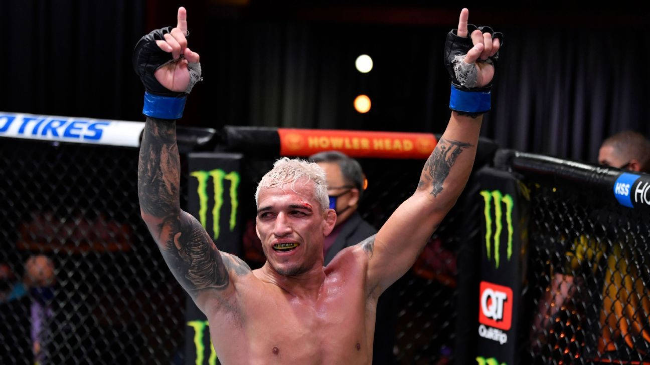 MMA 桌布 壁紙 — 一位勝利的混合武術家，漂白頭髮和刺青，在帶有贊助商標誌的籠子內高舉雙拳慶祝勝利。