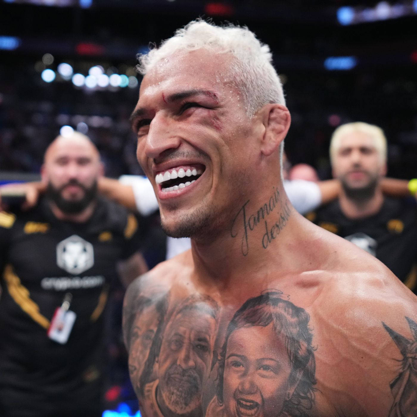 MMA 桌布 壁紙 — 一位勝利的混合武術家，漂白頭髮和家庭刺青，在八角籠中戰鬥後勝利大笑。