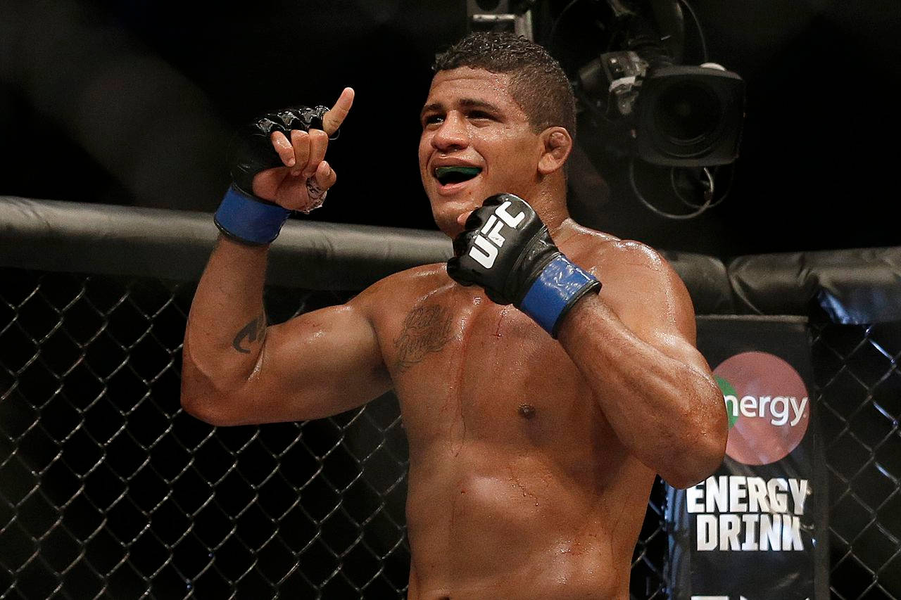 UFC 桌布 壁紙 — 一位勝利的混合武術家在UFC八角籠內以勝利的姿態和燦爛的笑容慶祝。