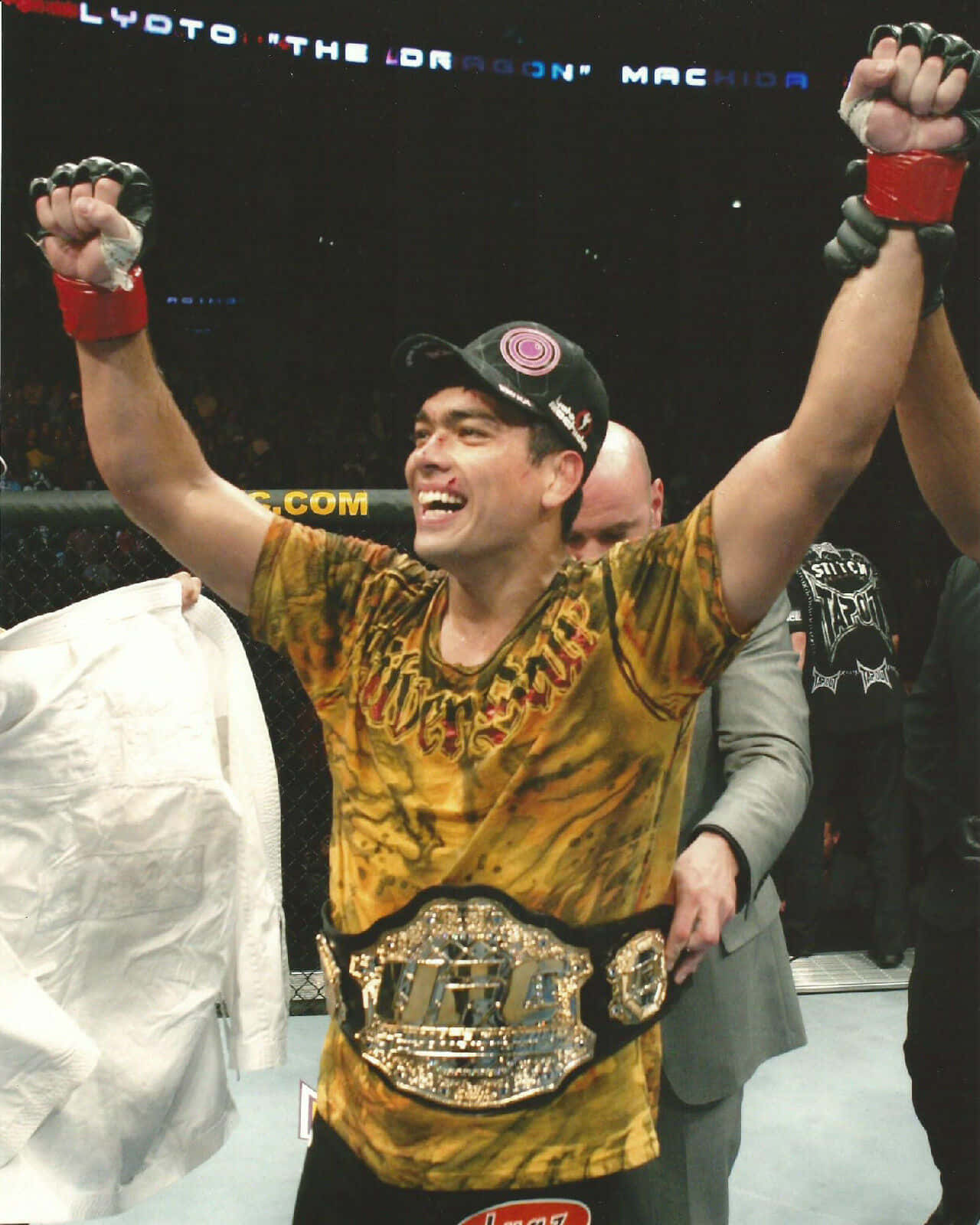 筆電 桌布 壁紙 — 一位勝利的混合武術家在UFC八角籠內舉起拳頭慶祝勝利，並佩戴冠軍腰帶。