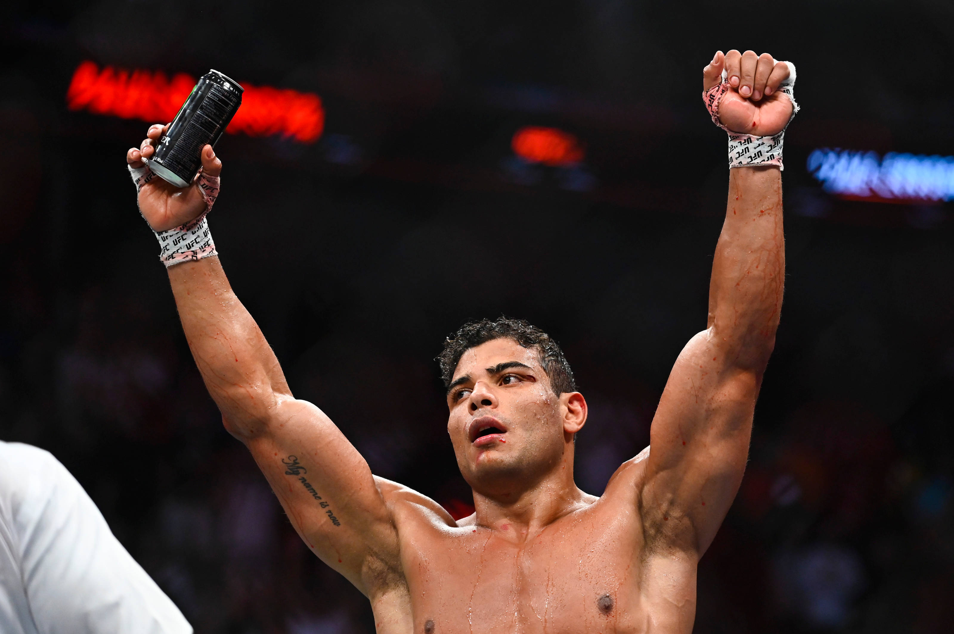 UFC 桌布 壁紙 — 一位勝利的混合武術家在場館燈光下高舉拳頭和罐頭慶祝勝利。